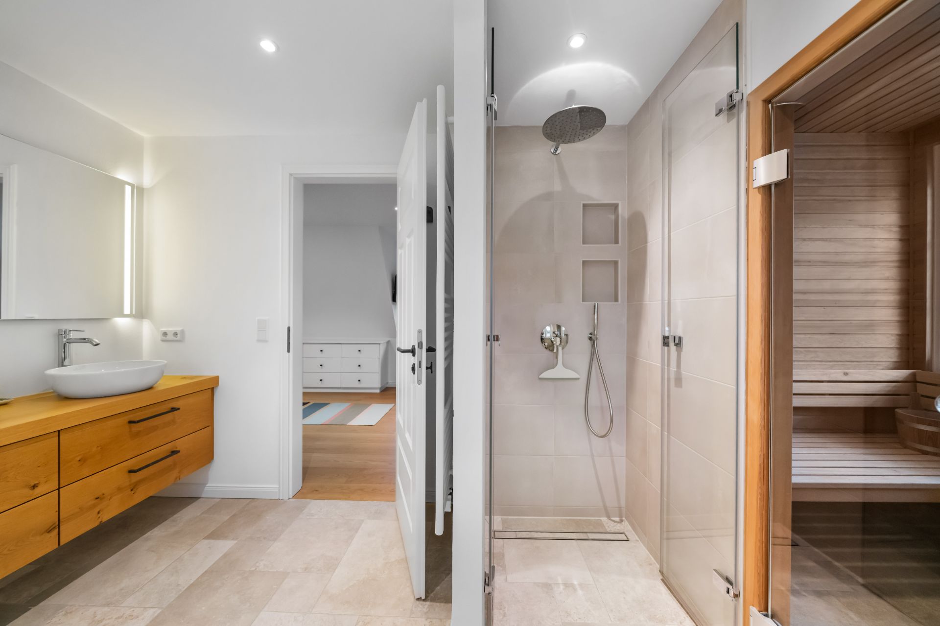 Modernes Badezimmer mit Holzmöbeln, Dusche mit Glastür und einer Sauna aus Holz.