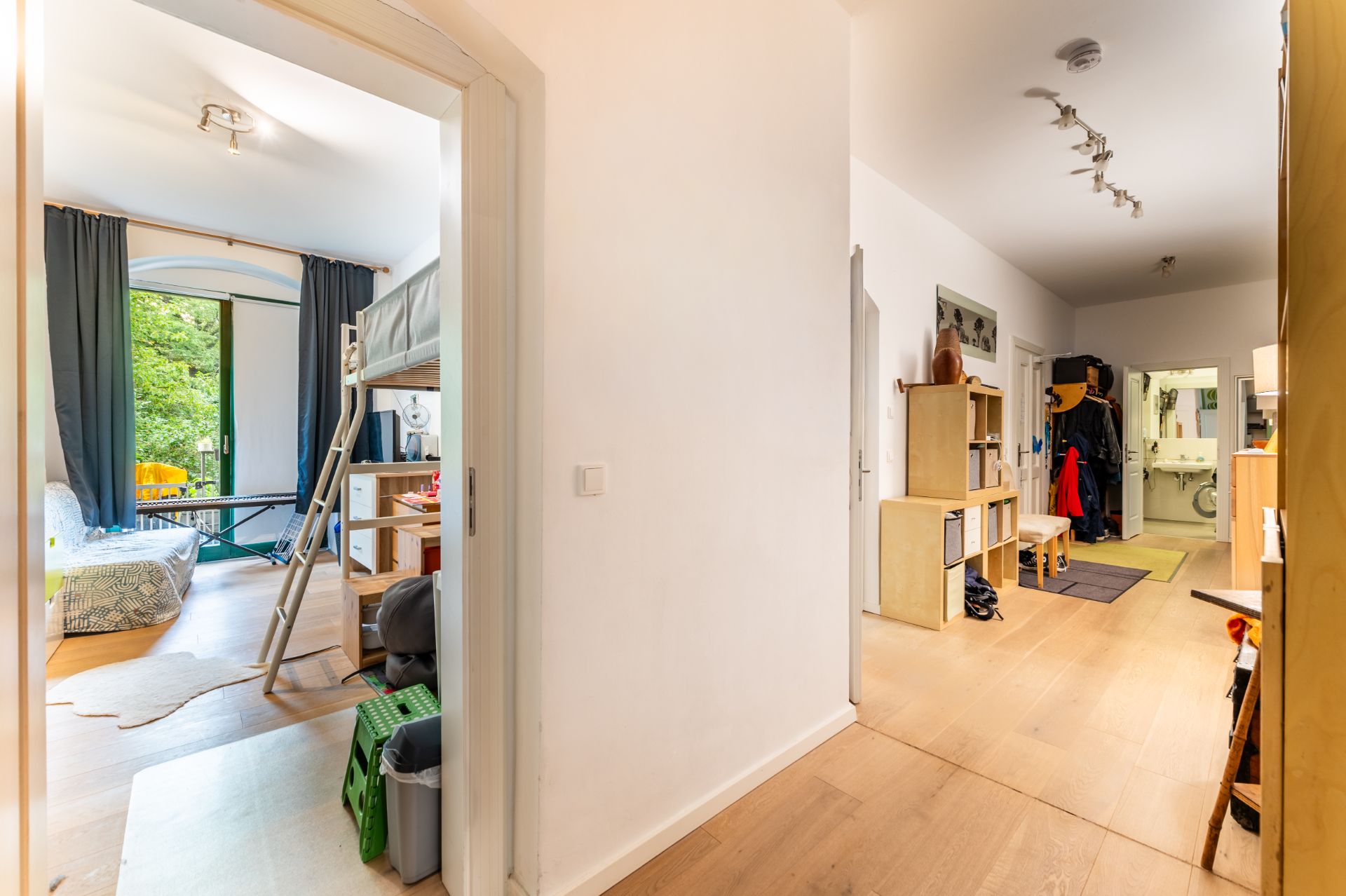 Flur mit Blick in ein Kinderzimmer mit Etagenbett und großem Fenster sowie Garderobe im Eingangsbereich.