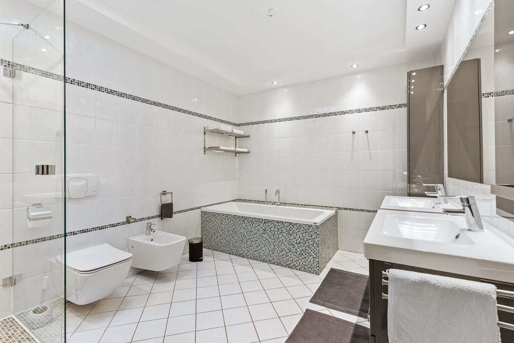 Modernes weißes Badezimmer mit Badewanne, Dusche, WC, Bidet und Doppelwaschbecken.