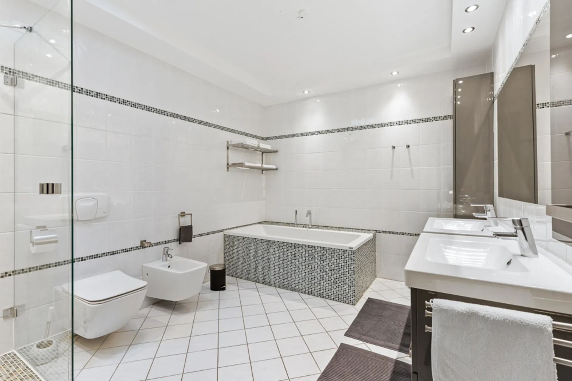 Modernes weißes Badezimmer mit Badewanne, Dusche, WC, Bidet und Doppelwaschbecken.