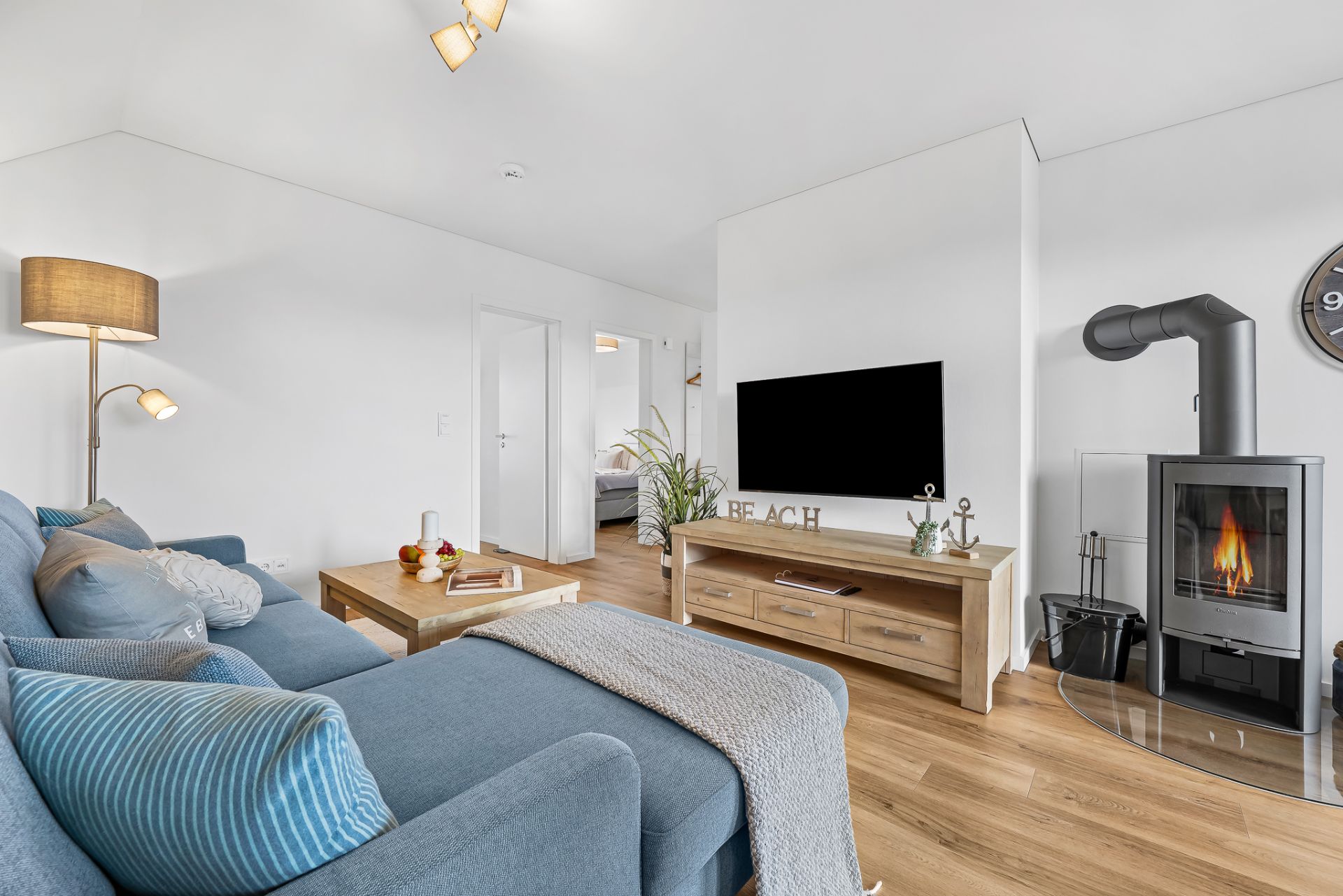 Modernes Wohnzimmer mit blauem Sofa, Holzfußboden, Fernseher und Kamin.