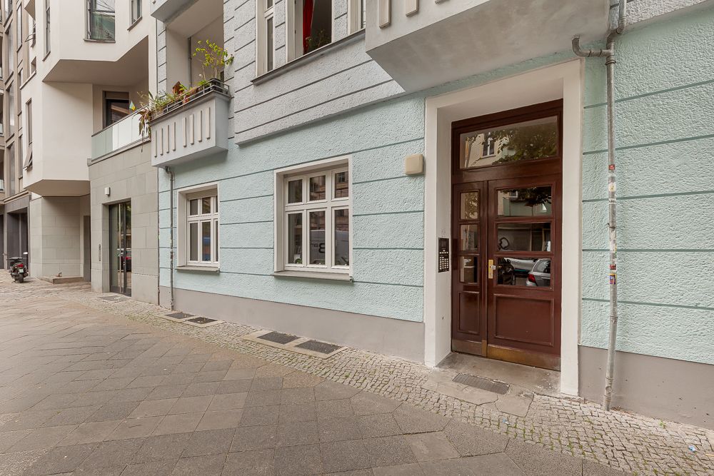 Hauseingang mit brauner Tür und zwei weißen Fenstern an blau gestrichener Fassade.