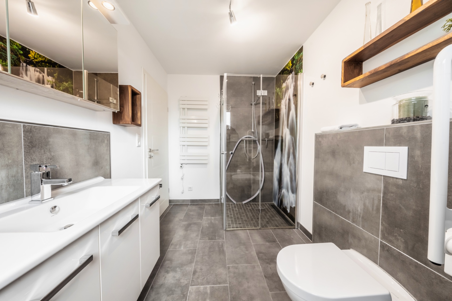 Modernes Badezimmer mit Dusche, WC, Waschbecken und grauen Fliesen.