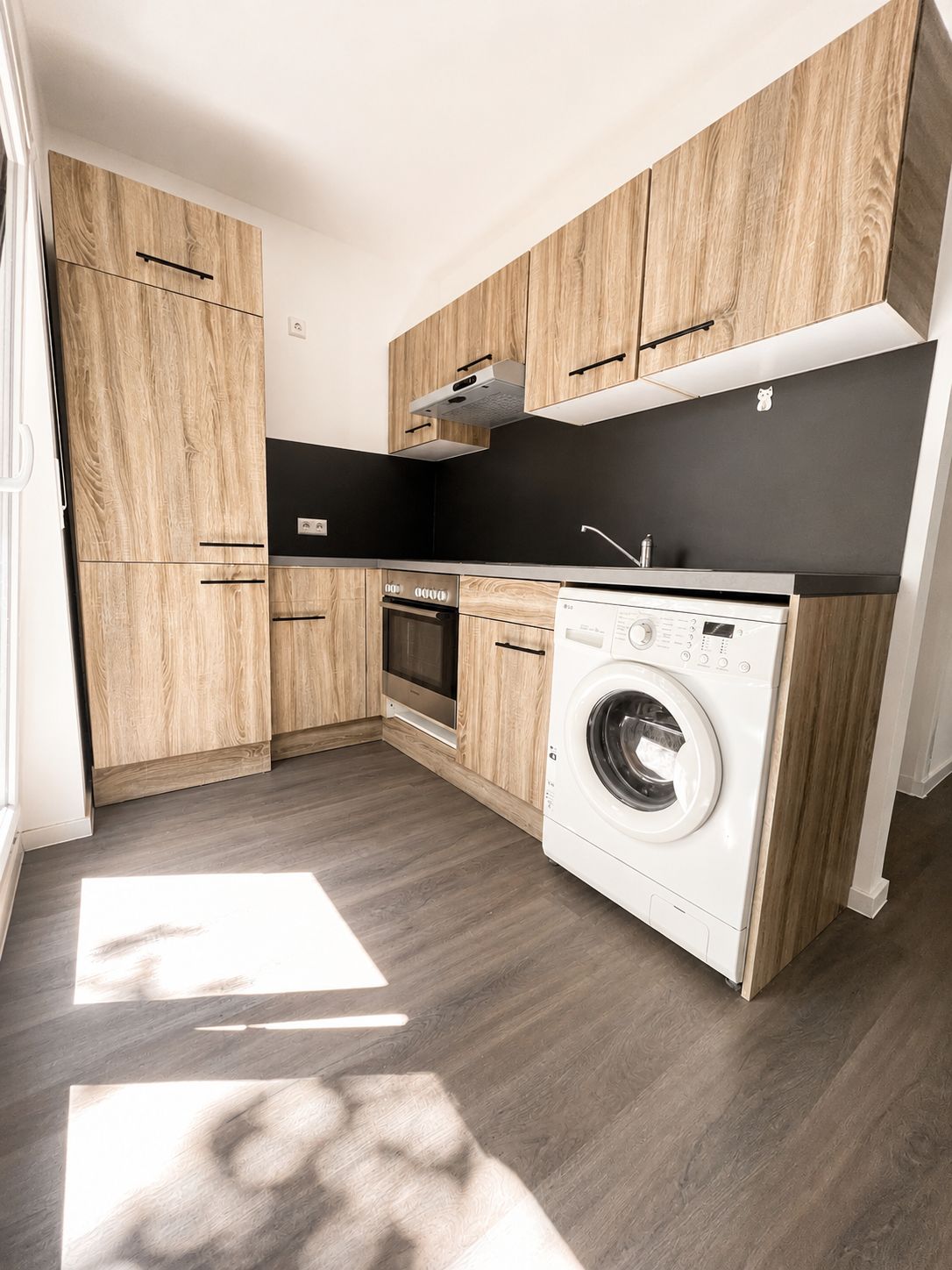 Moderne Einbauküche mit Holzfronten, Backofen, Waschmaschine und hellem Boden.
