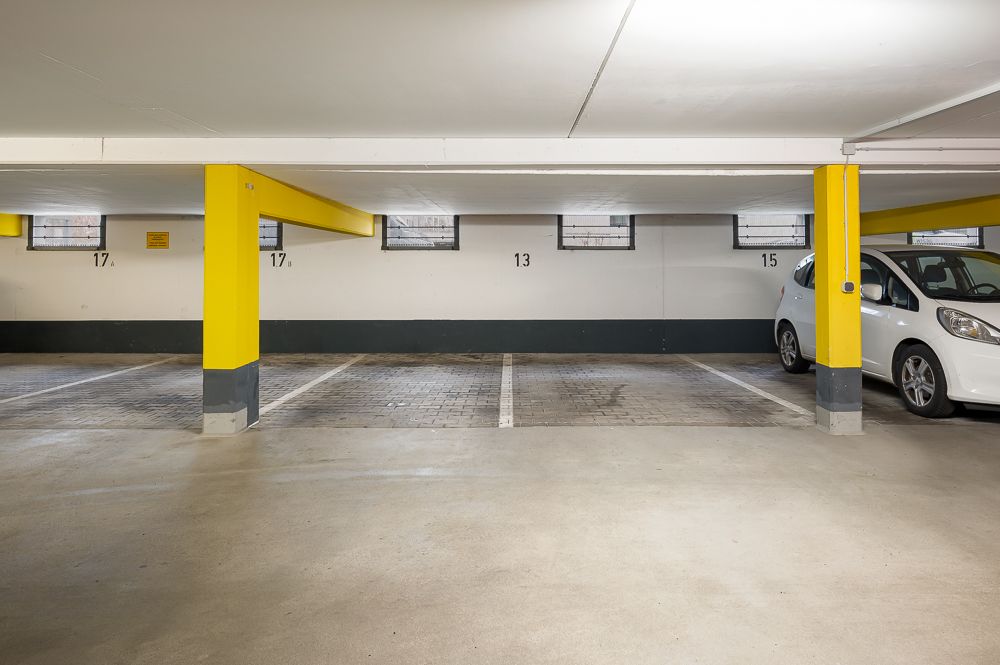 Parkplätze in einer Tiefgarage mit gelben Säulen und einem weißen Auto rechts.