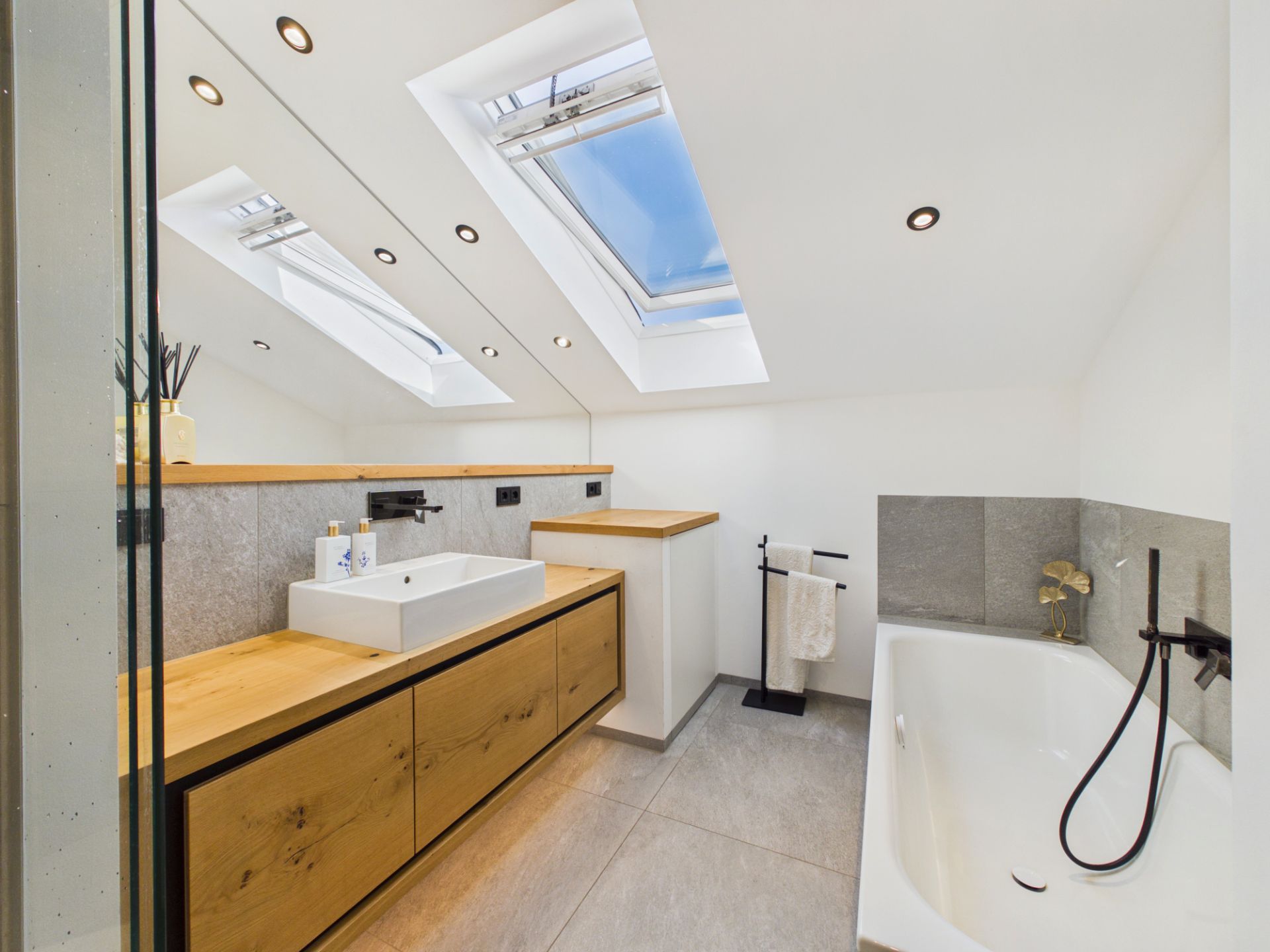 Modernes Bad mit Dachfenster, Holzmöbeln, Waschbecken und Badewanne.