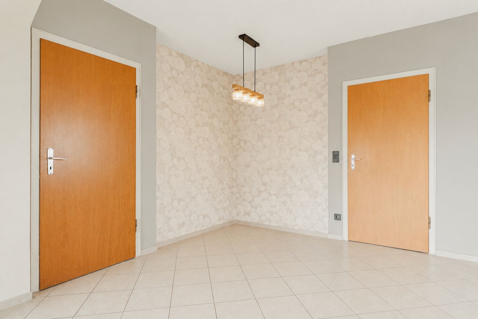 Flur mit zwei Holztüren, beigem Fliesenboden und moderner Deckenleuchte.