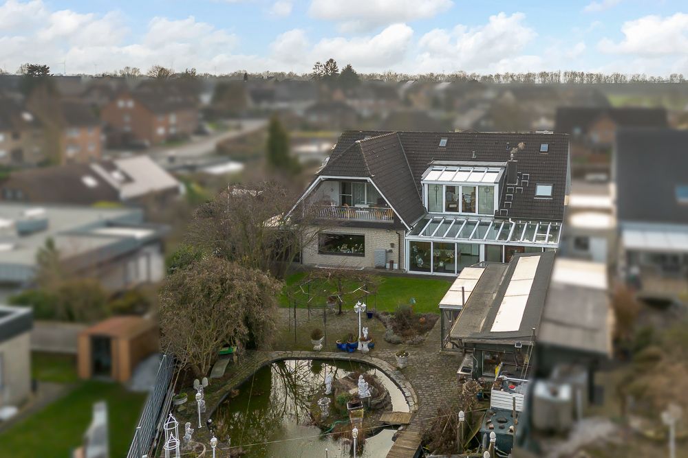 Wohnhaus mit Wintergarten und großem Garten mit Teich und Wegen, aus der Vogelperspektive.