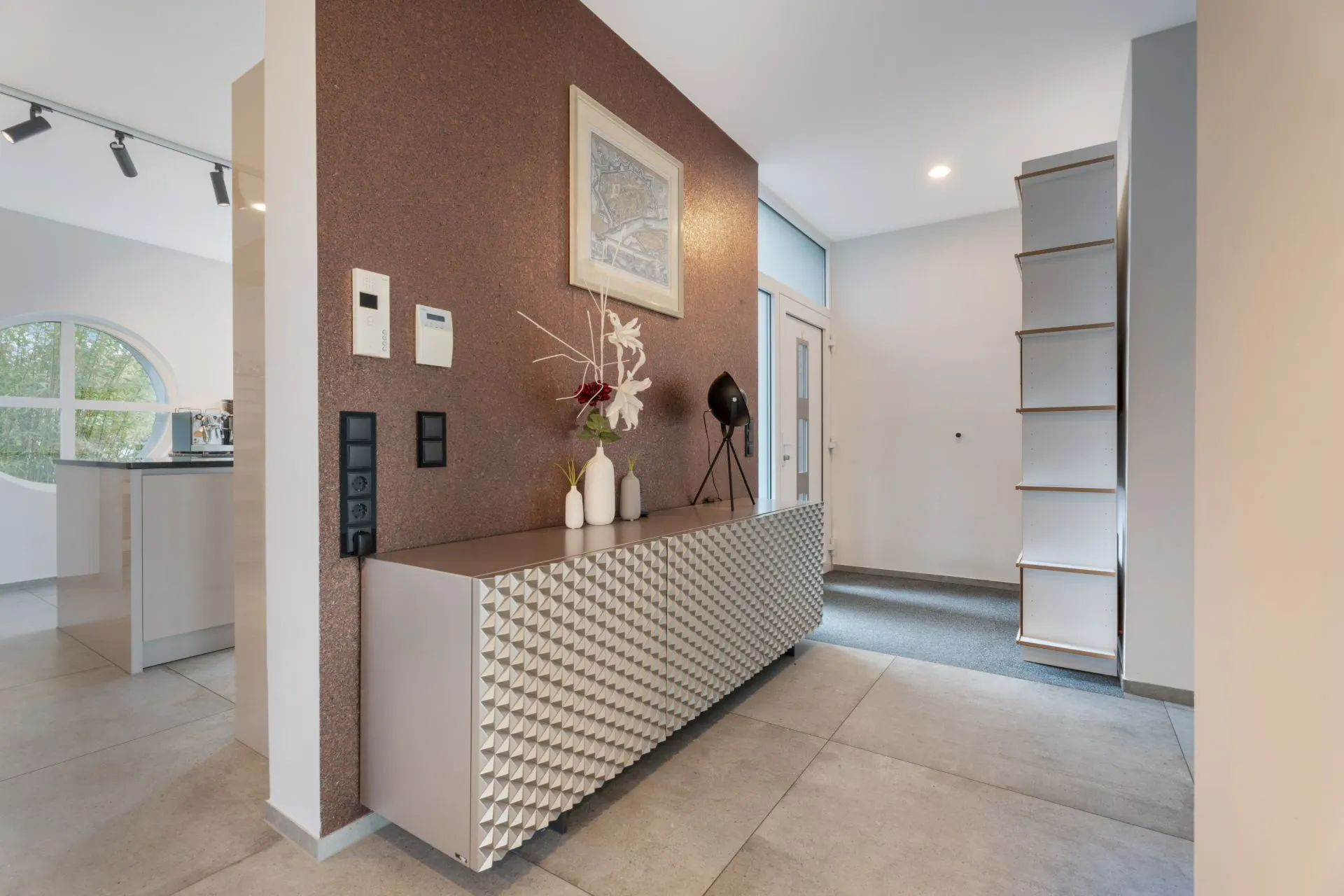 Moderner Flur mit Sideboard, Dekovasen, Wandbild und Regal neben einer Eingangstür.