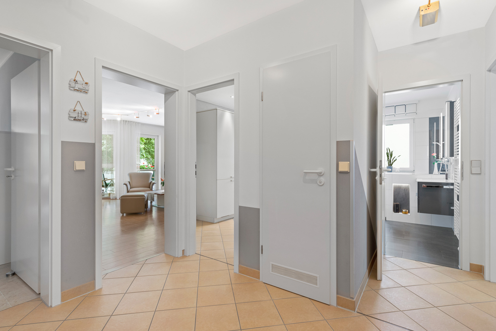 Heller Flur mit Türen zu Wohnzimmer, Küche und anderen Räumen, Fliesenboden und neutraler Wandfarbe.