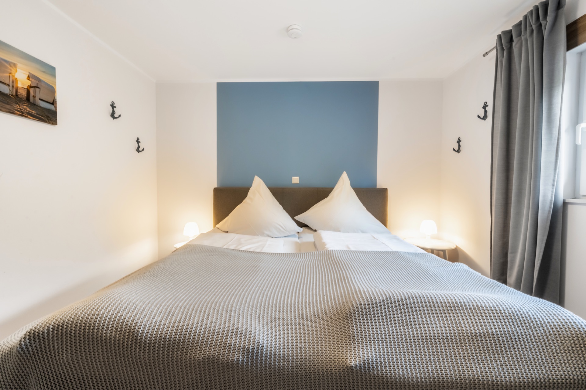 Schlafzimmer mit Doppelbett, Nachttischen, Lampen und einem Bild an der Wand.