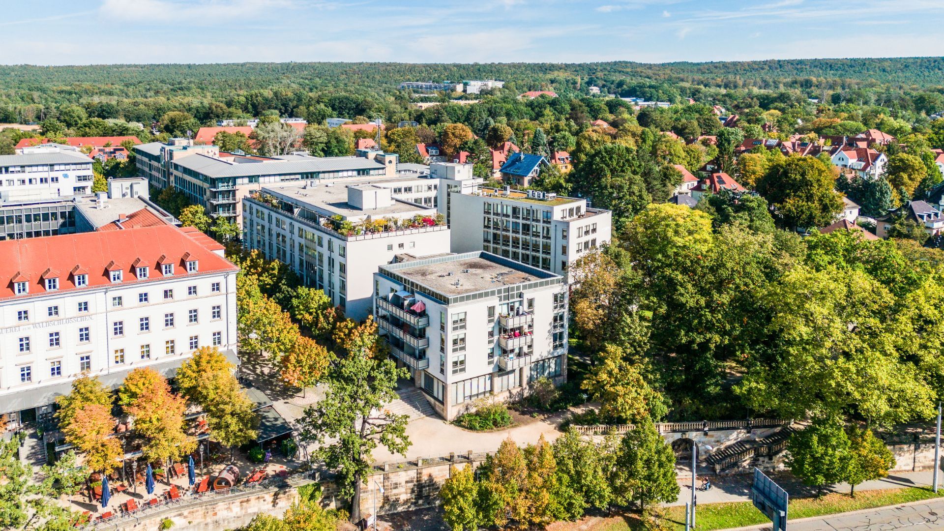 Mehrere moderne Wohngebäude mit Balkonen und umliegenden Bäumen aus der Vogelperspektive.