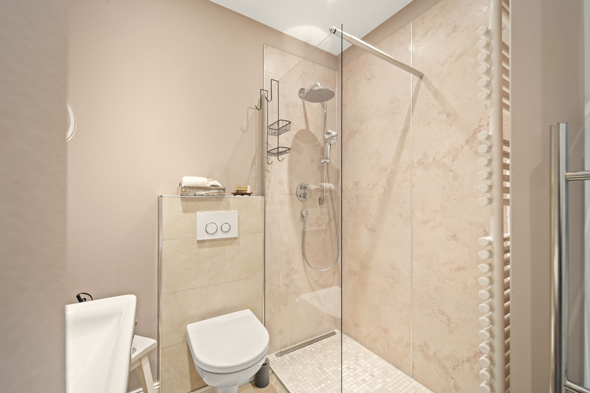 Modernes Badezimmer mit Dusche, Wandtoilette und kleinem Waschbecken.