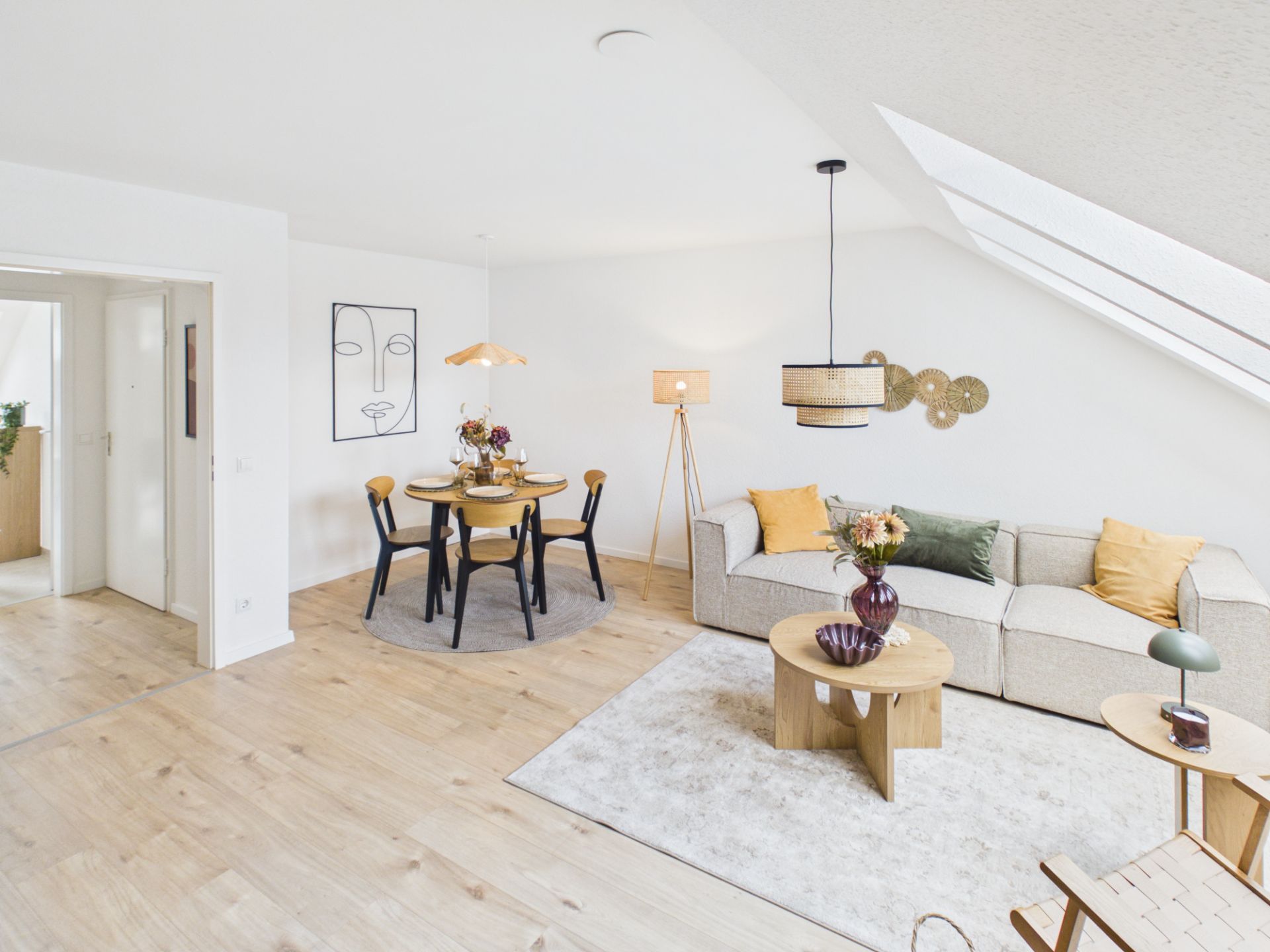 Helles Wohnzimmer mit Sofa, Couchtisch, Esstisch und großen Dachfenstern.