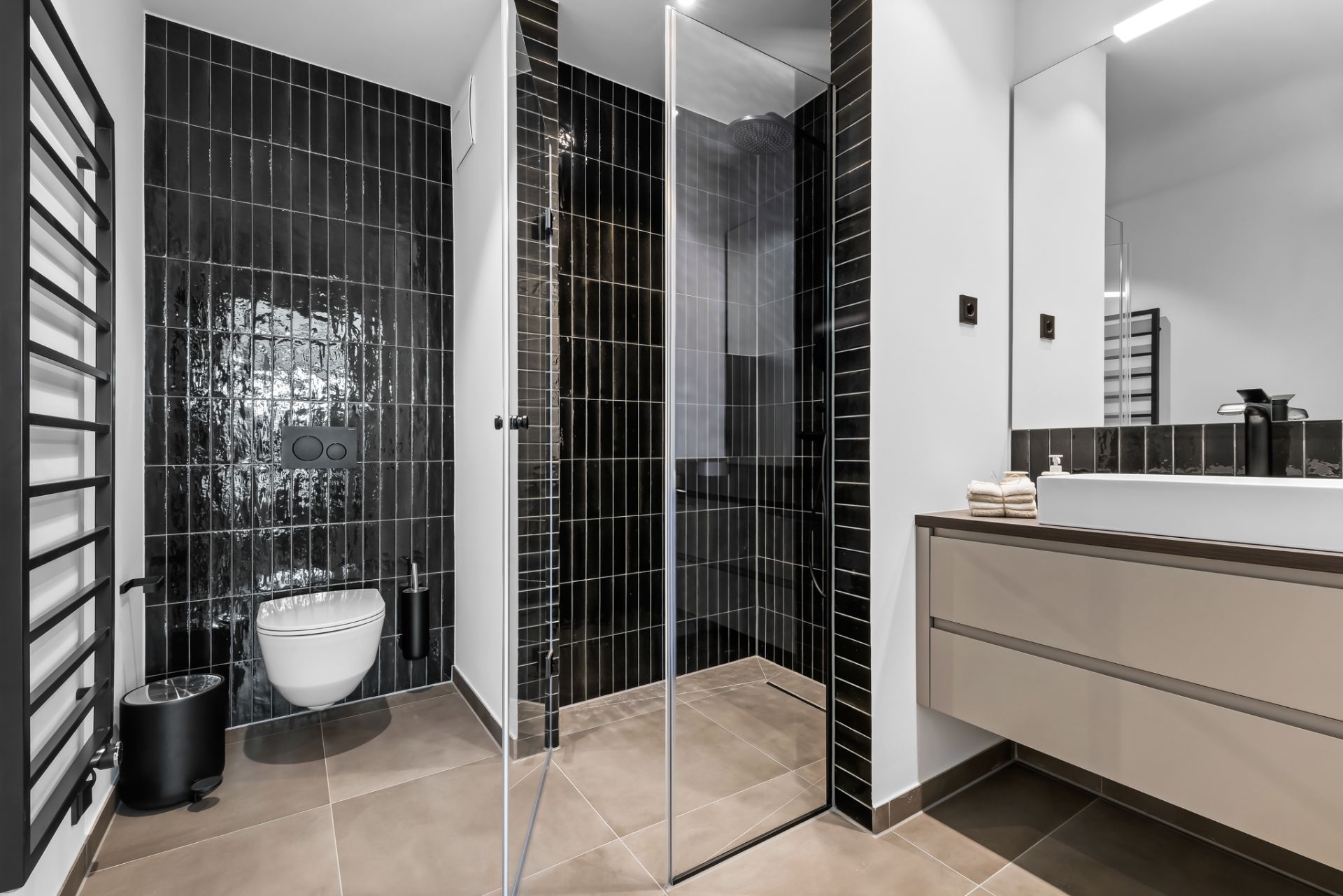 Modernes Badezimmer mit bodengleicher Dusche, Hänge-WC, Waschbecken und schwarzer Wandverkleidung.