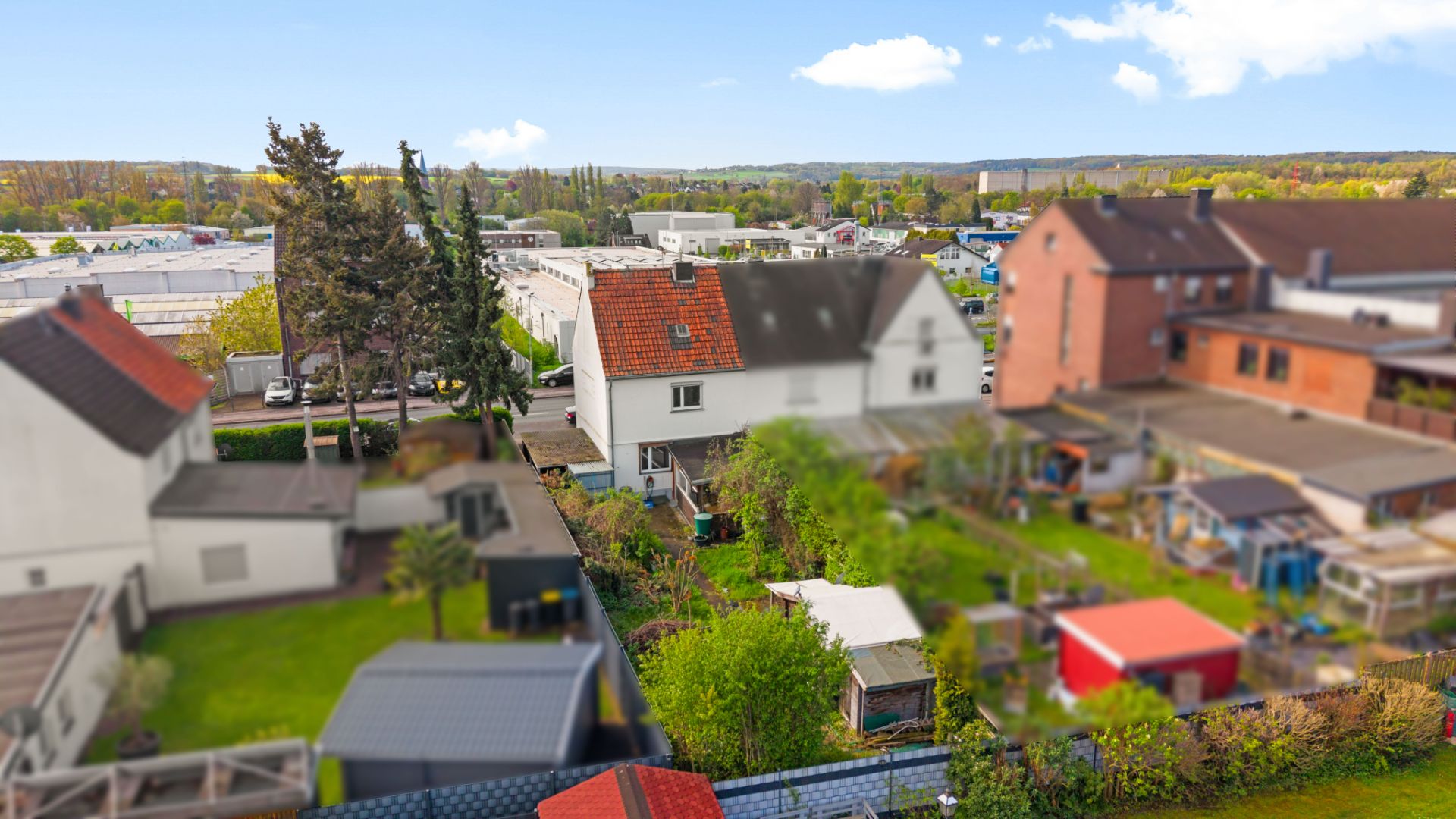 Blick auf mehrere Wohnhäuser mit Gärten und Bäumen im Vordergrund.