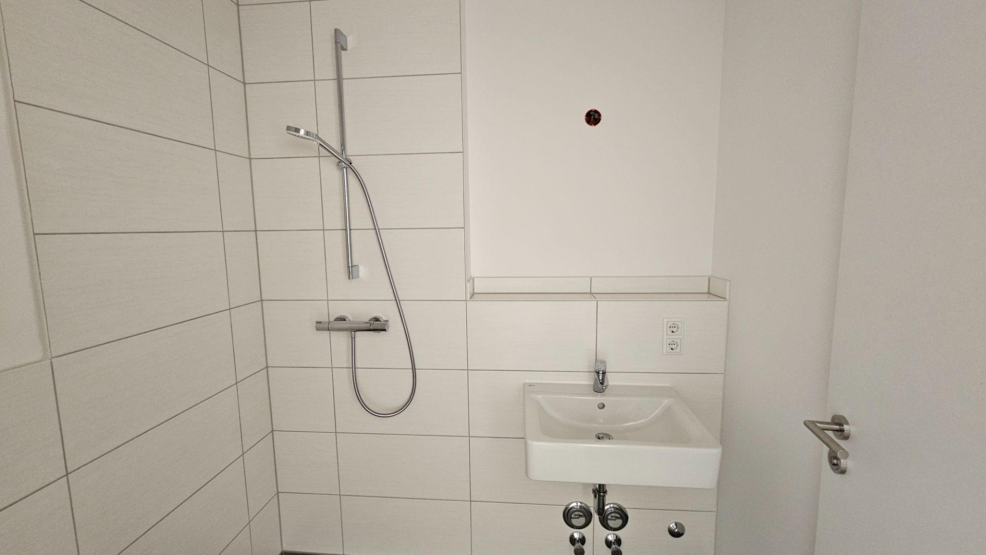 Modernes Badezimmer mit Dusche, Waschbecken und weißen Wandfliesen.