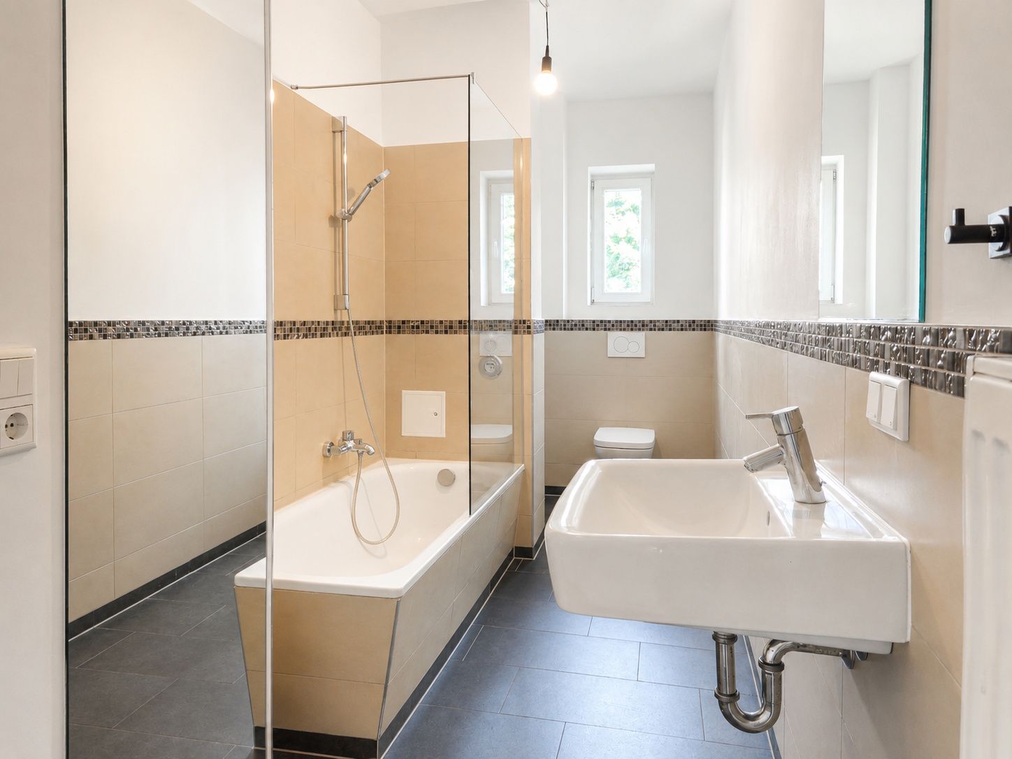 Modernes Badezimmer mit Badewanne, Waschbecken, Toilette und zwei Fenstern.