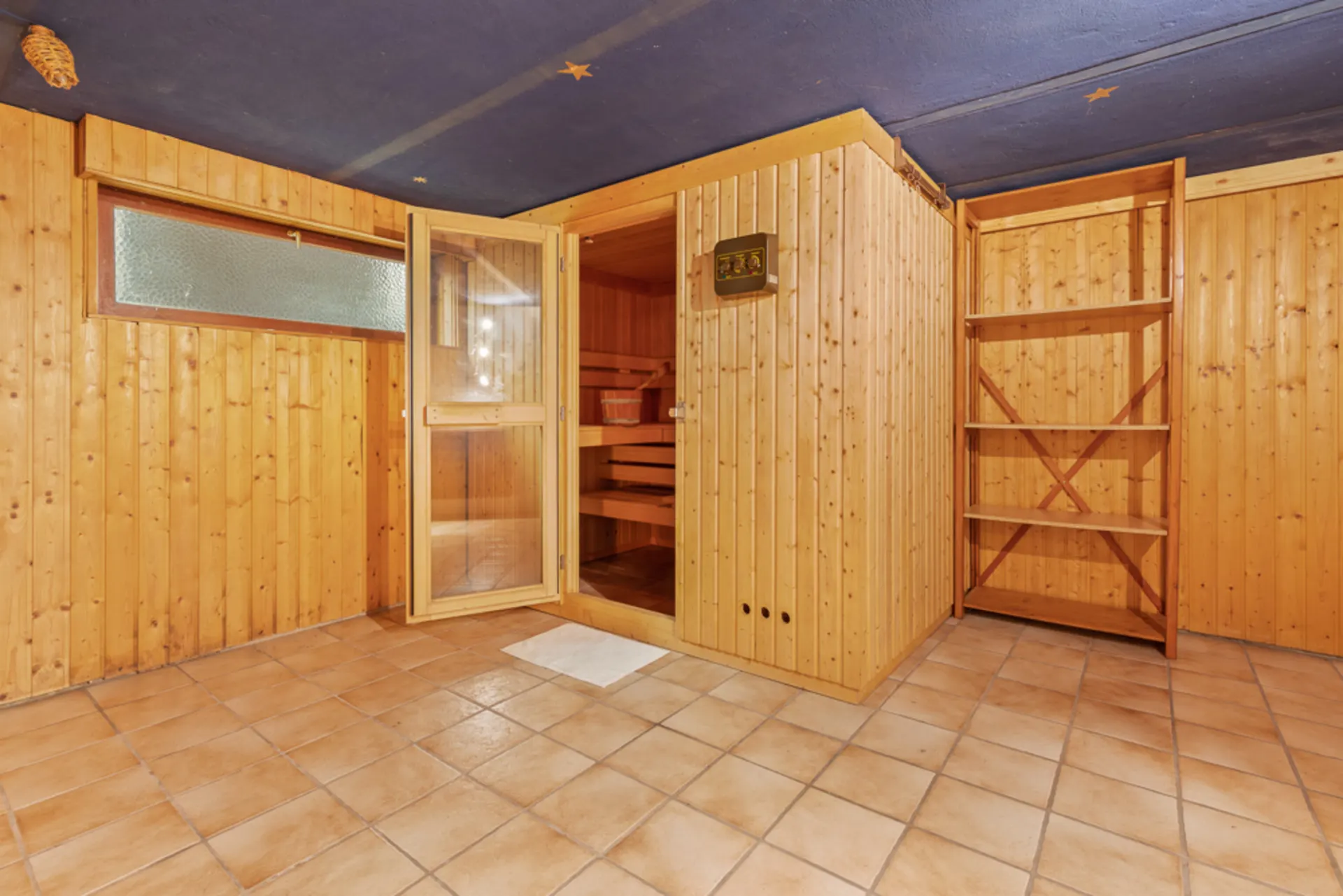 Holzvertäfelter Raum mit Sauna, offenem Regal und gefliestem Boden.