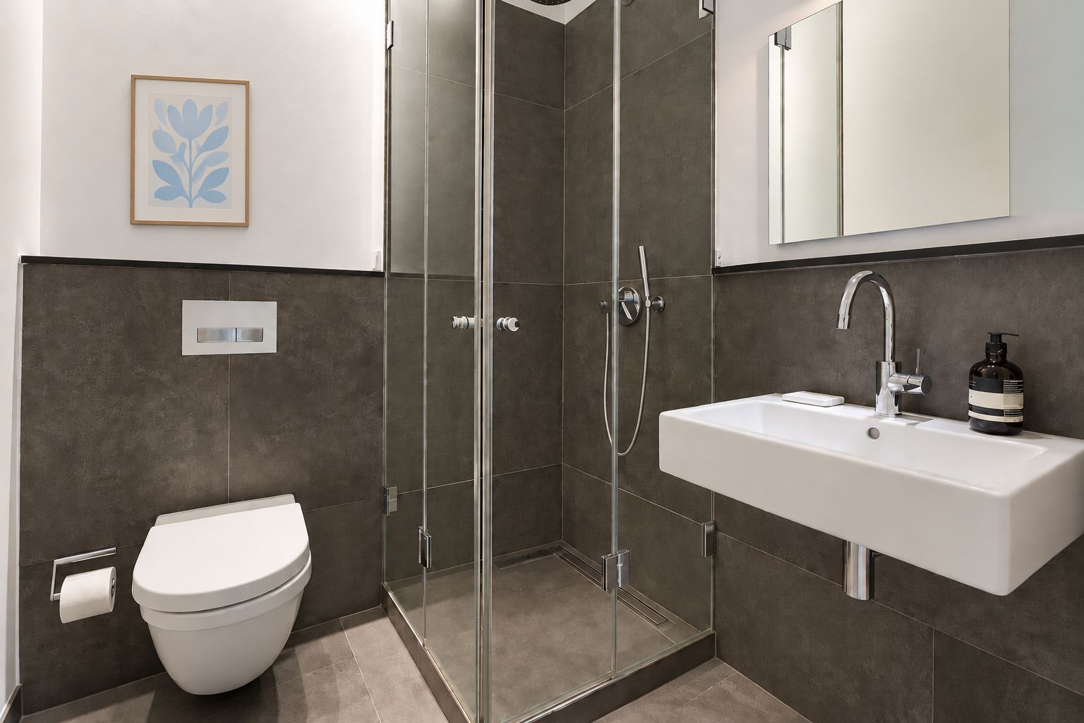 Modernes Bad mit bodenebener Dusche, Wandtoilette, Waschbecken und Spiegel.