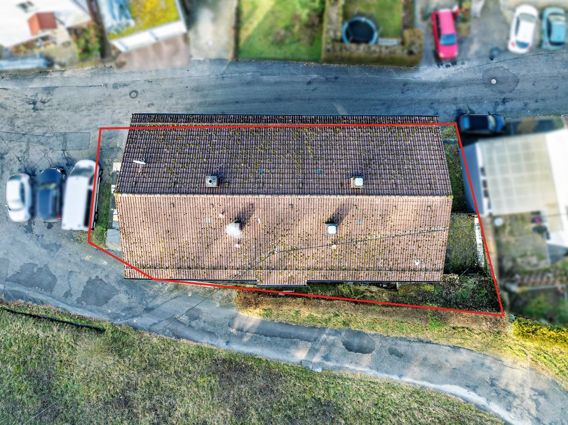 Luftaufnahme eines Hauses mit Ziegeldach, von roter Linie umrandet, an einer Straße gelegen.