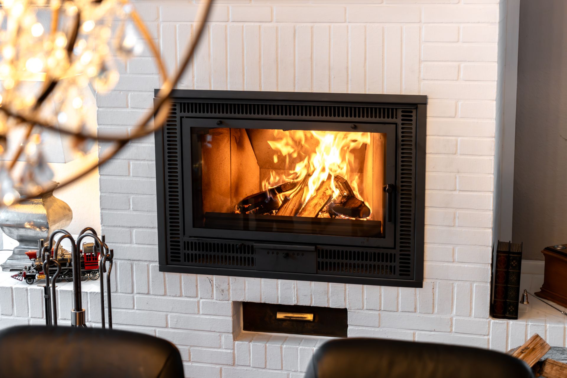 Kamin mit brennendem Feuerholz in einer weißen gemauerten Wand.