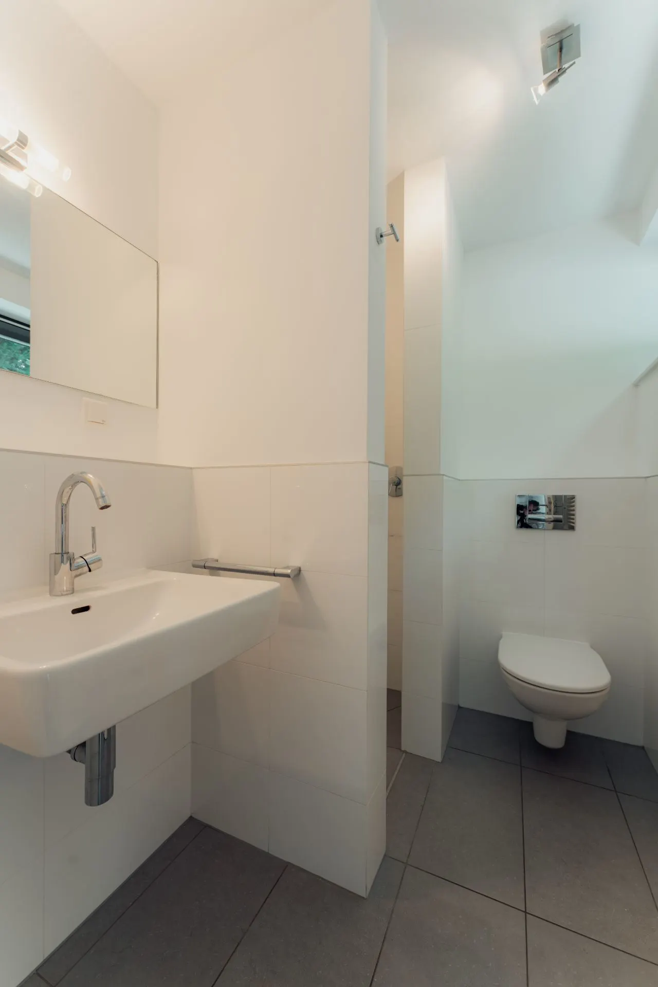Modernes Badezimmer mit Waschbecken, Spiegel und wandhängender Toilette.