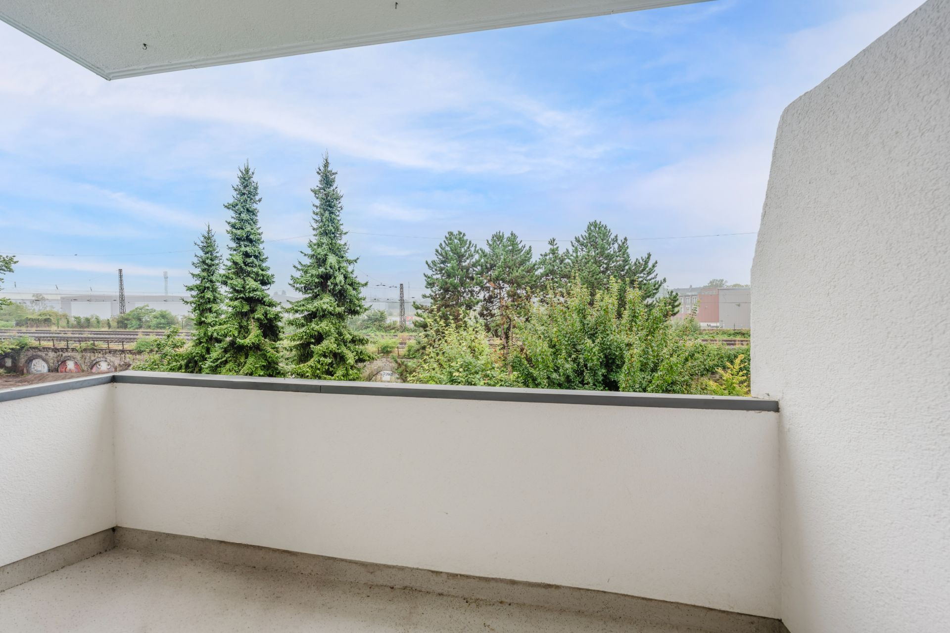 Balkon mit Blick auf Bäume und blauen Himmel.