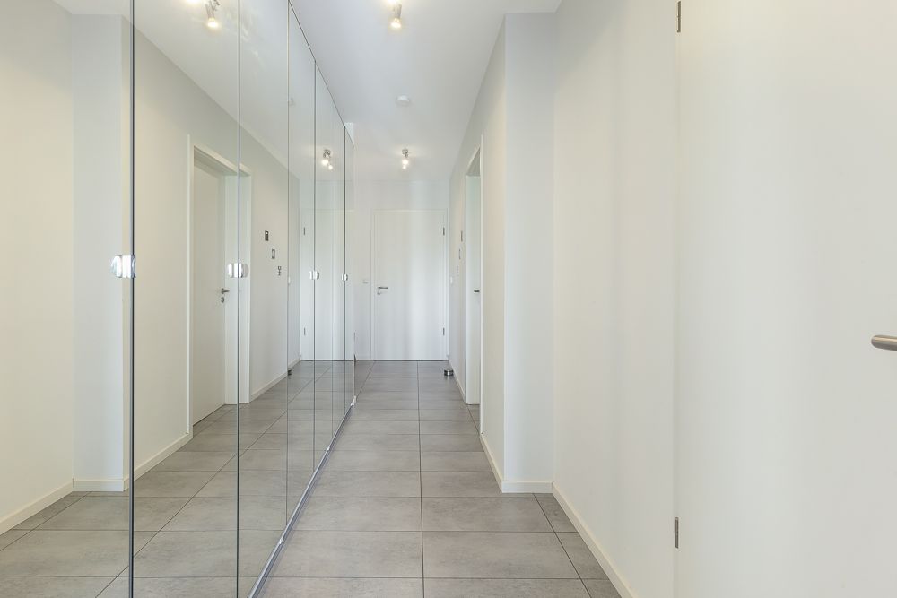 Heller Flur mit Fliesenboden und Spiegelschrank auf der linken Seite.