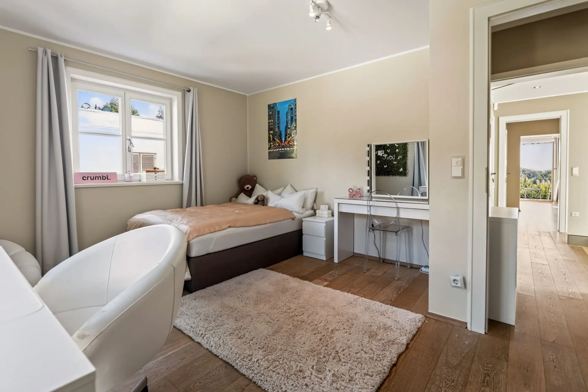 Helles Schlafzimmer mit Einzelbett, Schminktisch, Teppich und großem Fenster.