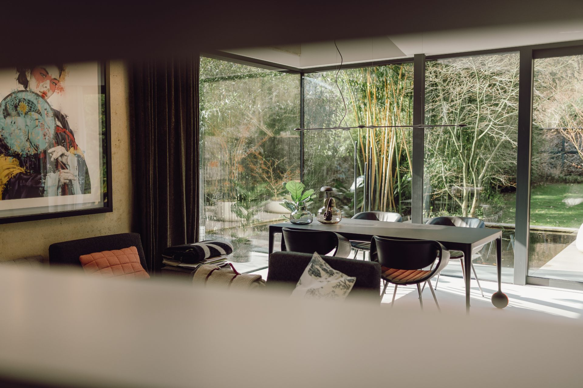 Modernes Wohnzimmer mit Essbereich, großen Fenstern und Blick auf den Garten.