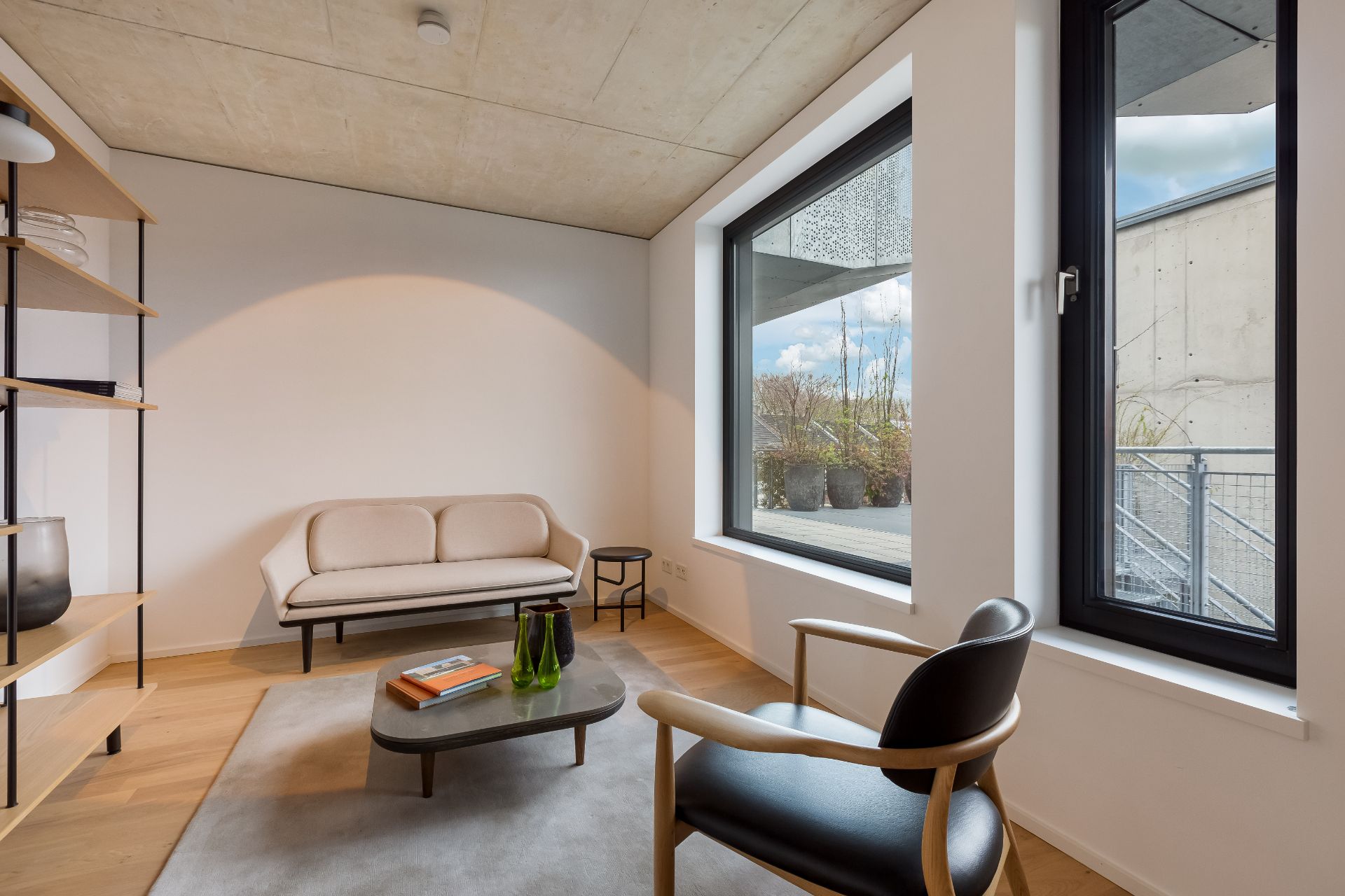 Modernes Wohnzimmer mit Sofa, Sessel, Couchtisch und großen Fenstern.