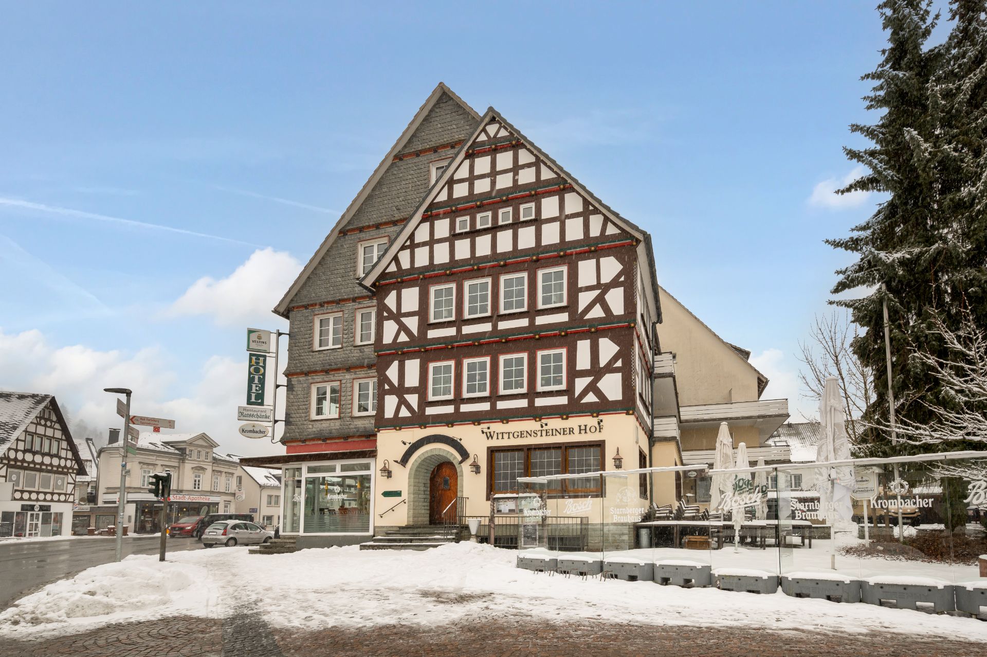 Fachwerkhaus mit mehreren Fenstern und verschneitem Vorplatz, bei Tageslicht aufgenommen.