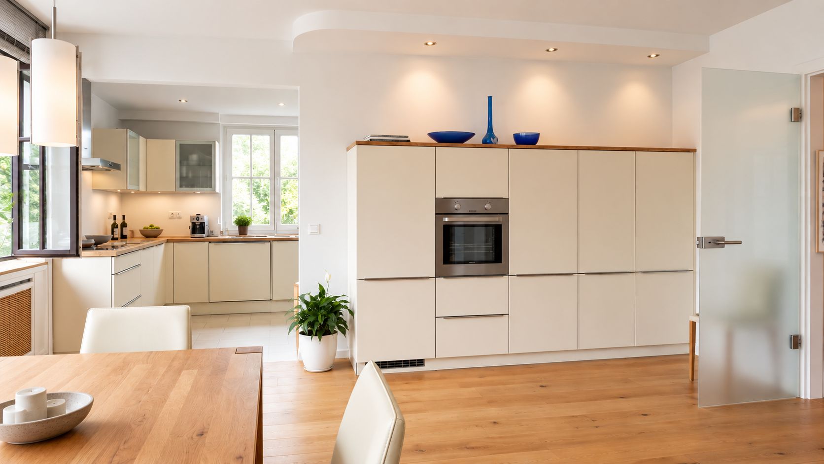 Helle, moderne Küche mit Einbauschränken, Holzfußboden und Esstisch mit Stühlen.