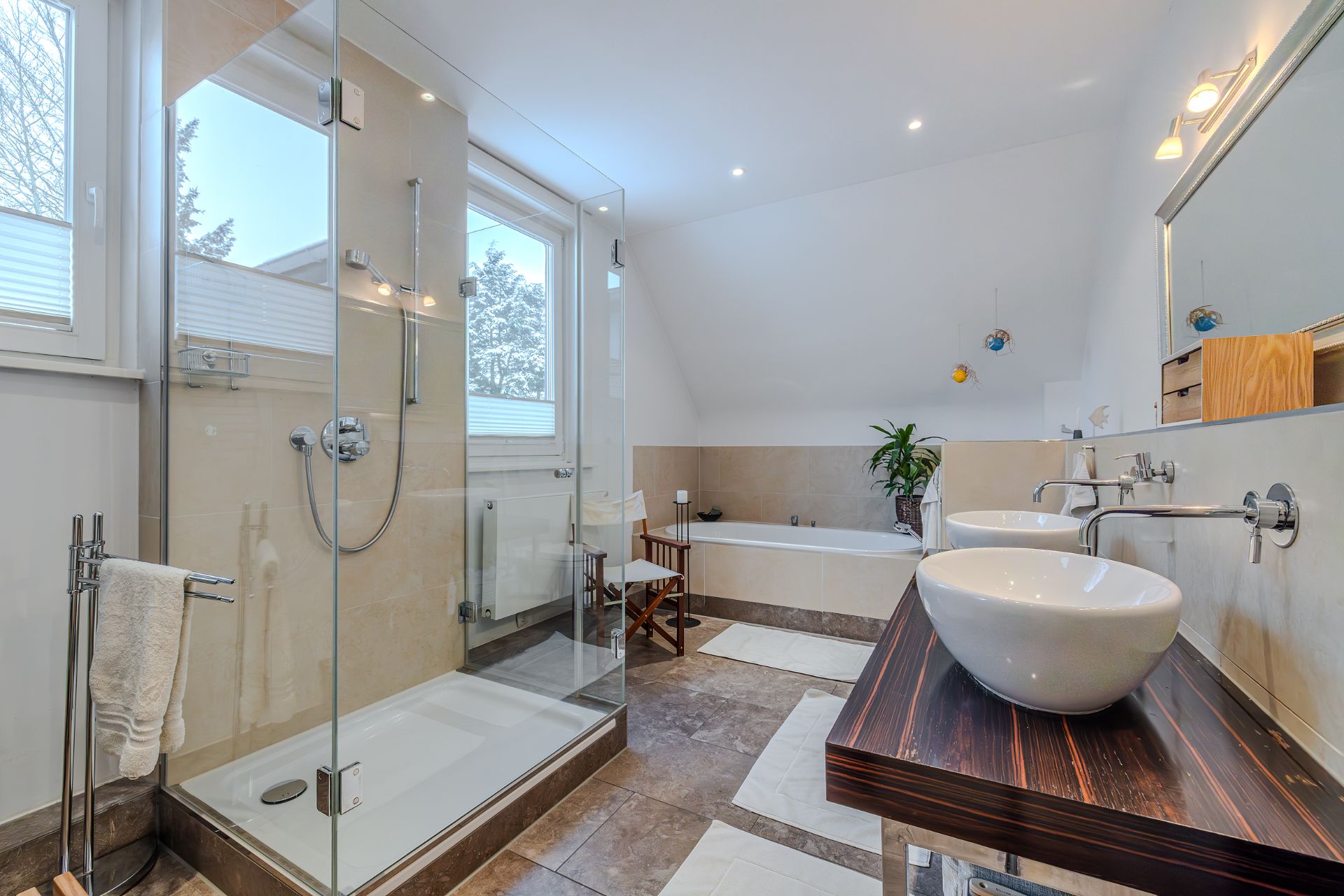 Modernes Badezimmer mit Glasdusche, Badewanne, zwei Waschbecken und großem Spiegel.