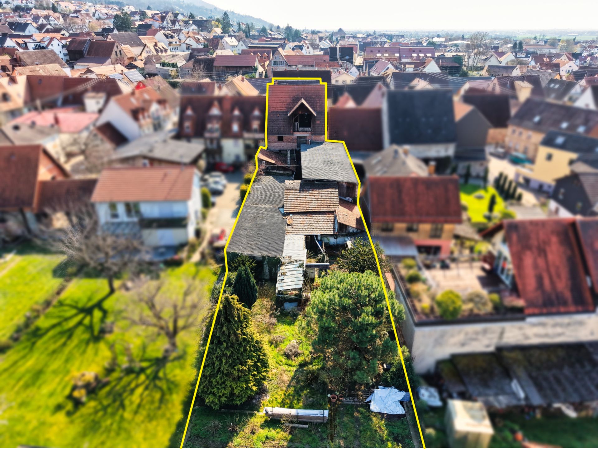 Luftaufnahme eines Grundstücks mit Haus und Garten, gelb umrandet.
