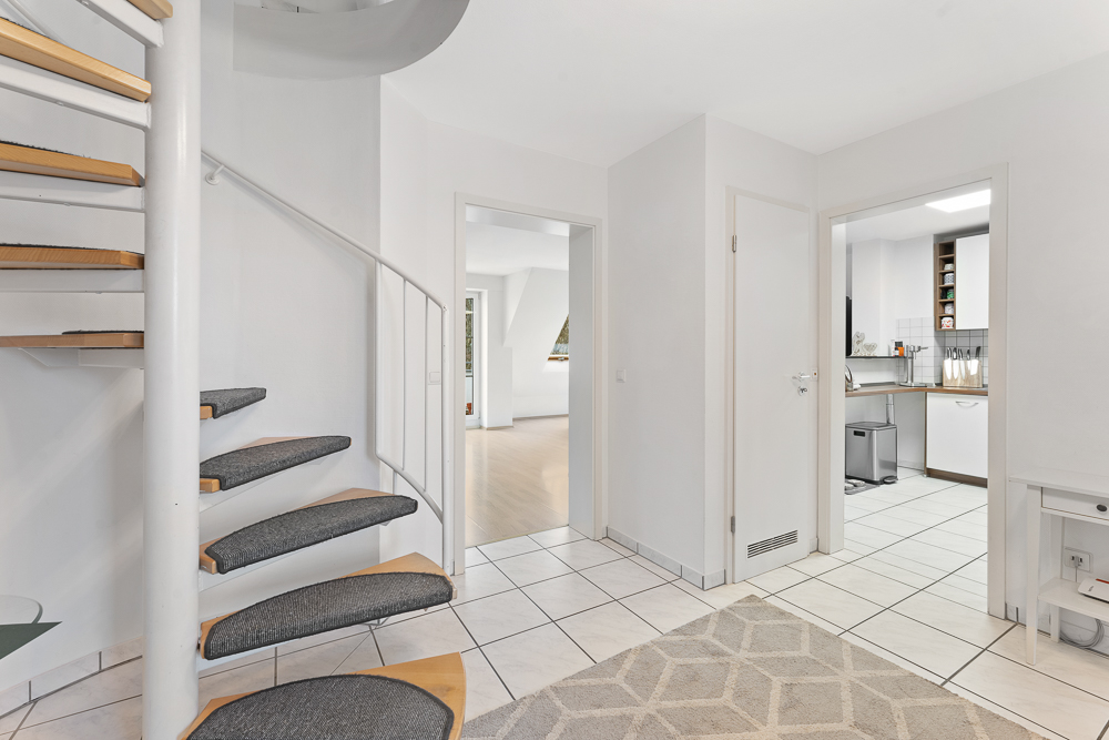 Helle Diele mit Wendeltreppe, Fliesenboden, Zugang zu Wohnzimmer und Küche.