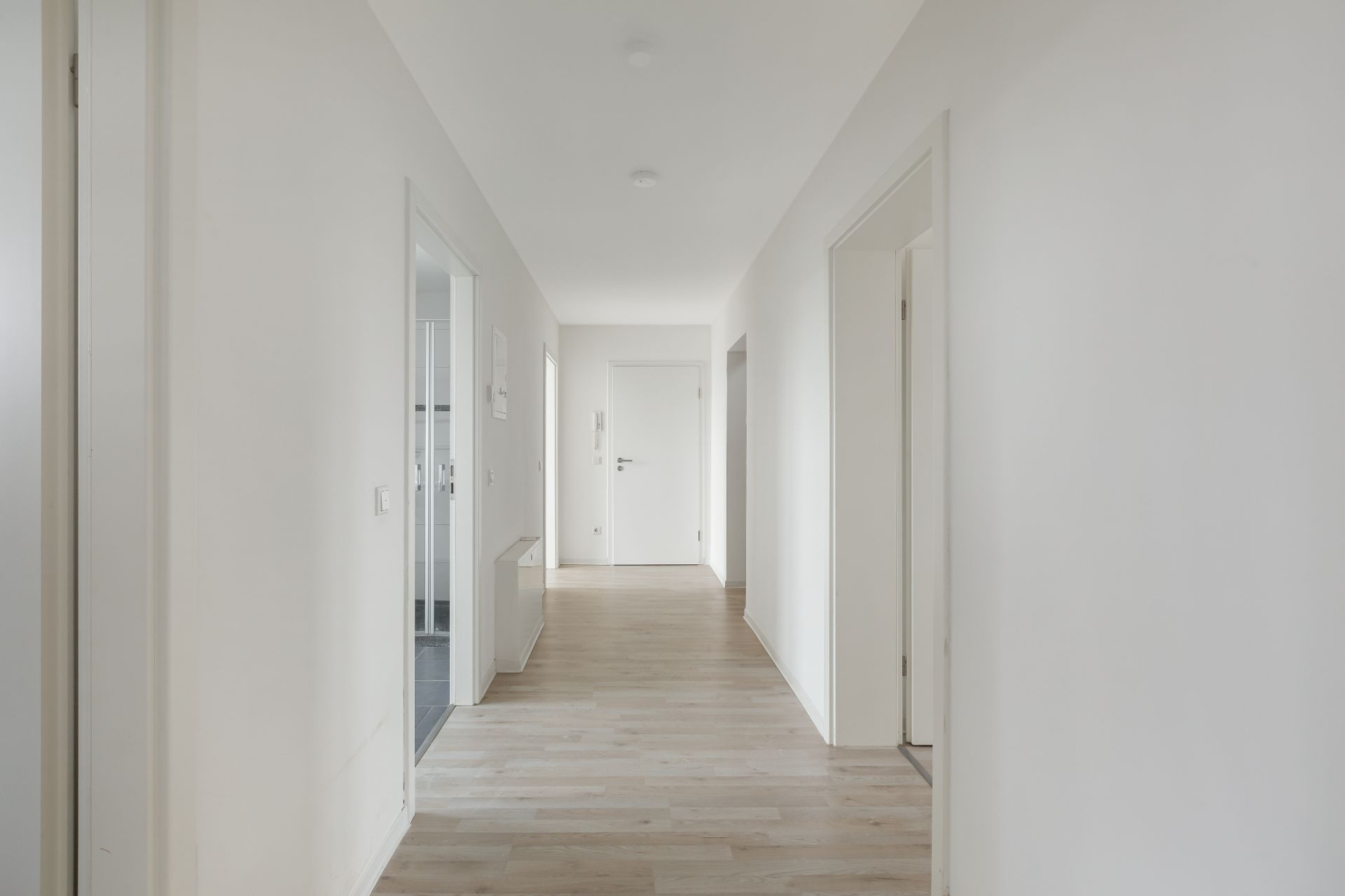 Heller Flur mit Holzboden und mehreren Zimmertüren in einer Wohnung.