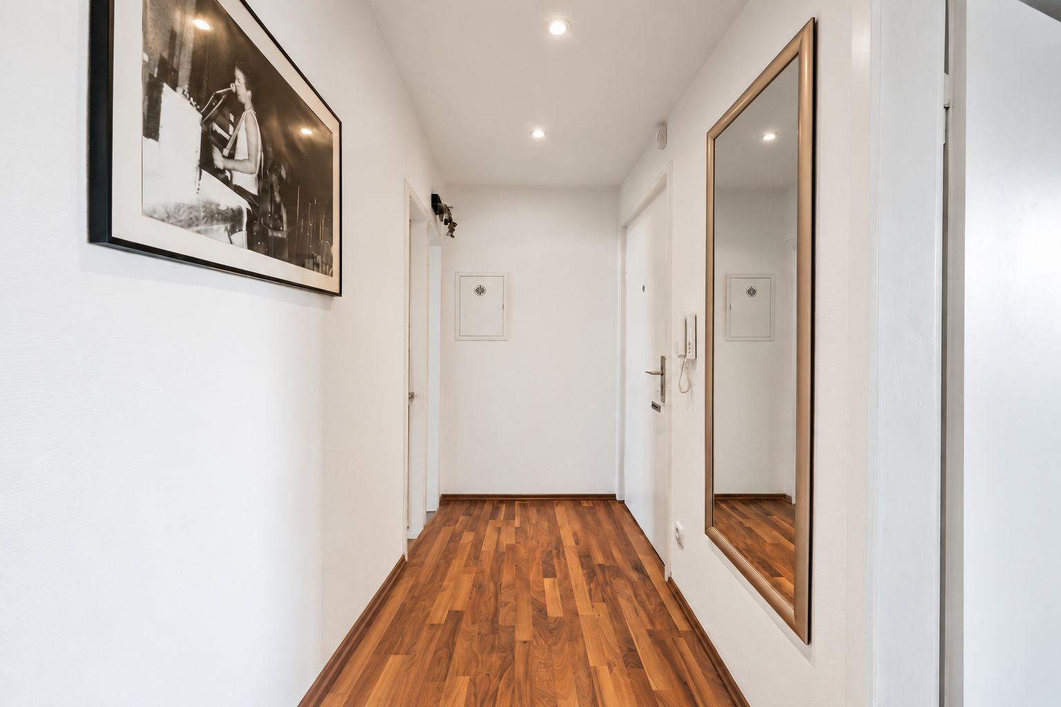 Heller Flur mit Holzfußboden, großem Spiegel und einem Wandbild.