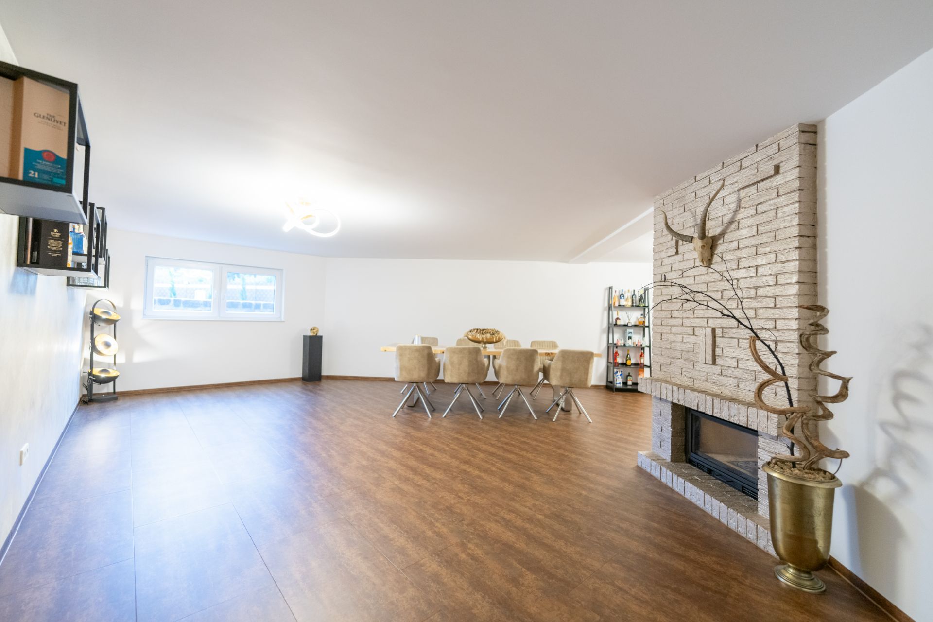 Großes Wohnzimmer mit Holzboden, Esstisch, Kamin und Dekoration an der Wand.