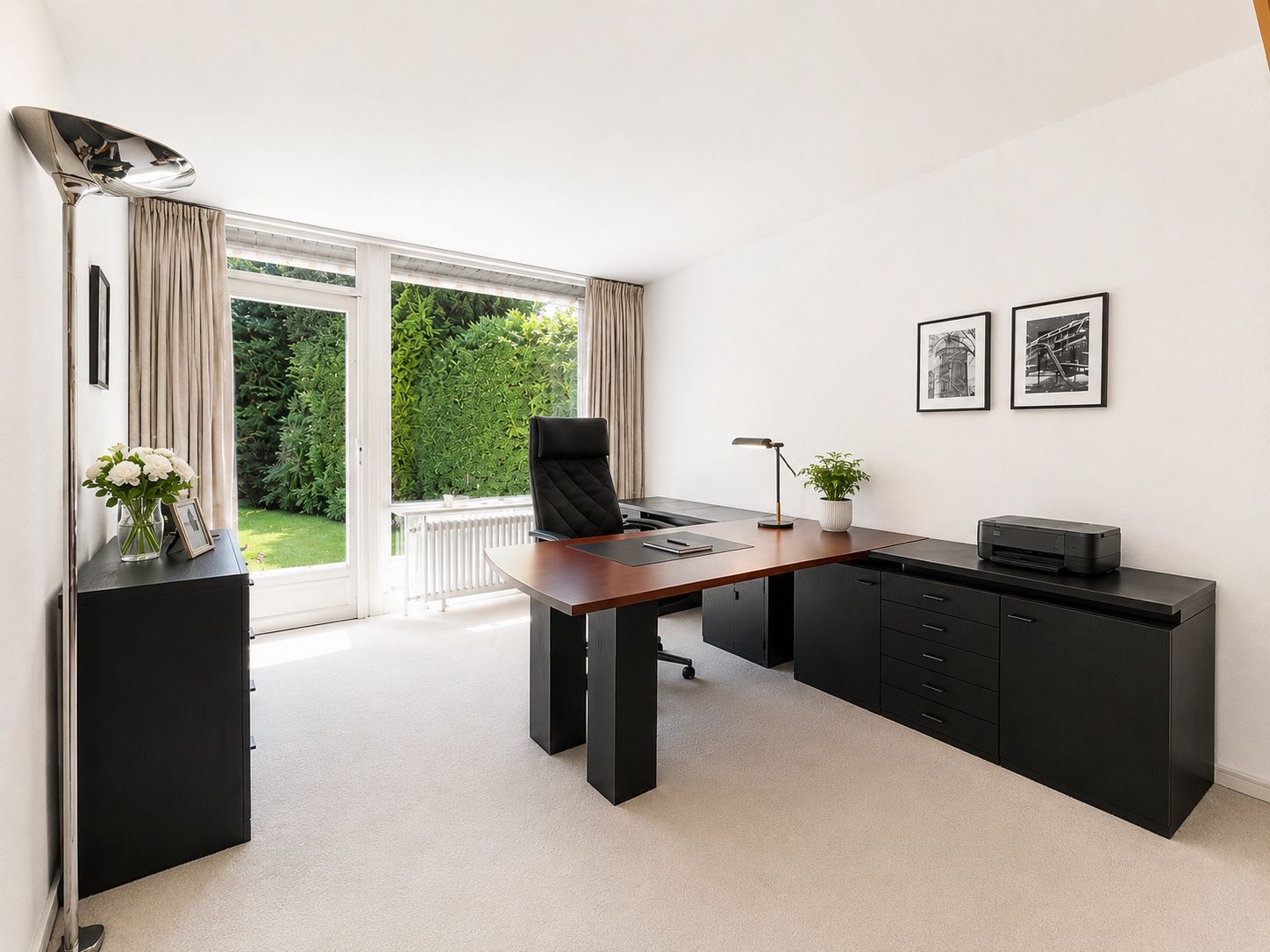 Modernes Arbeitszimmer mit großem Schreibtisch, Bürostuhl und Blick in einen Garten.