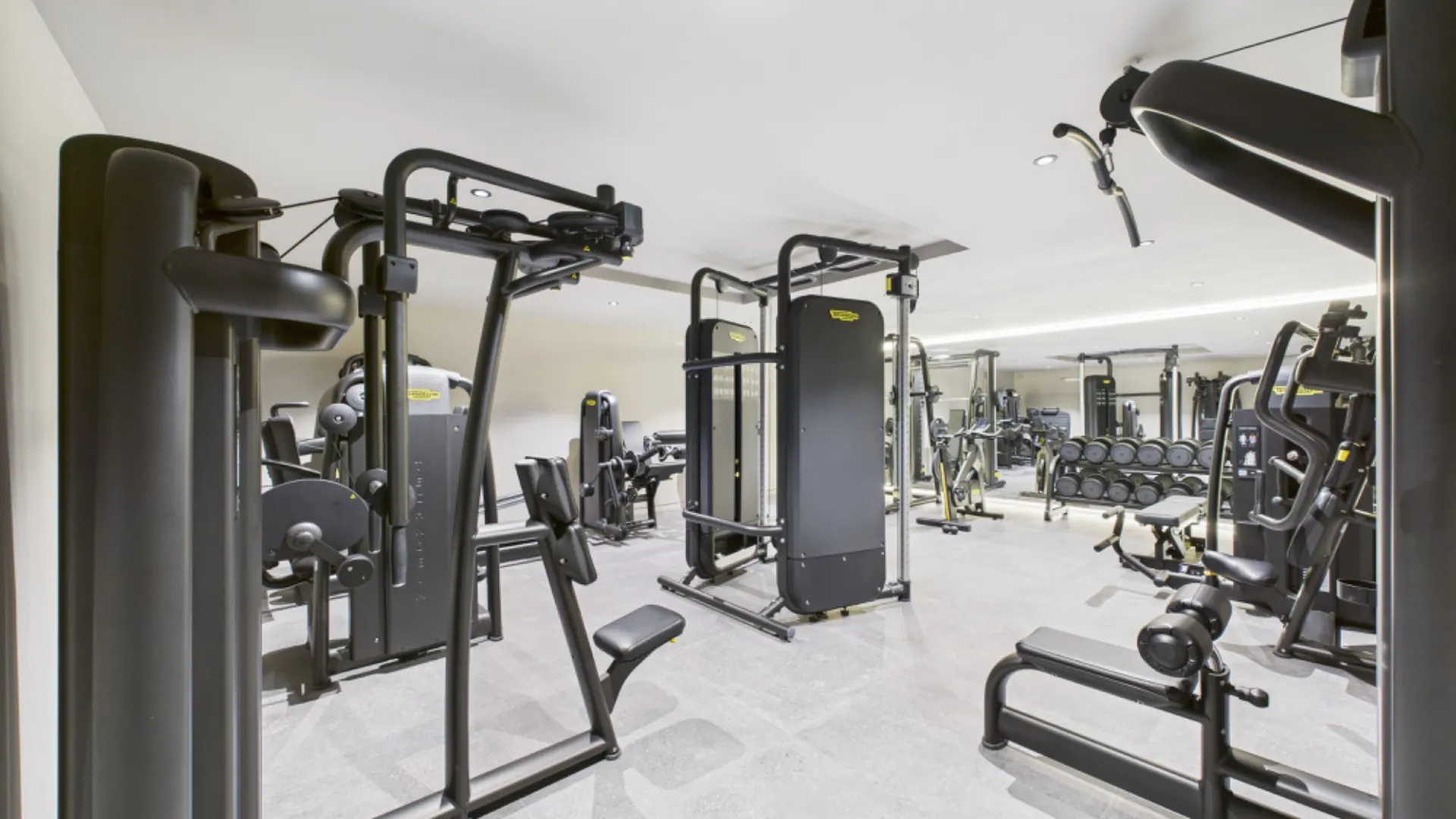 Heller Fitnessraum mit verschiedenen modernen Trainingsgeräten.
