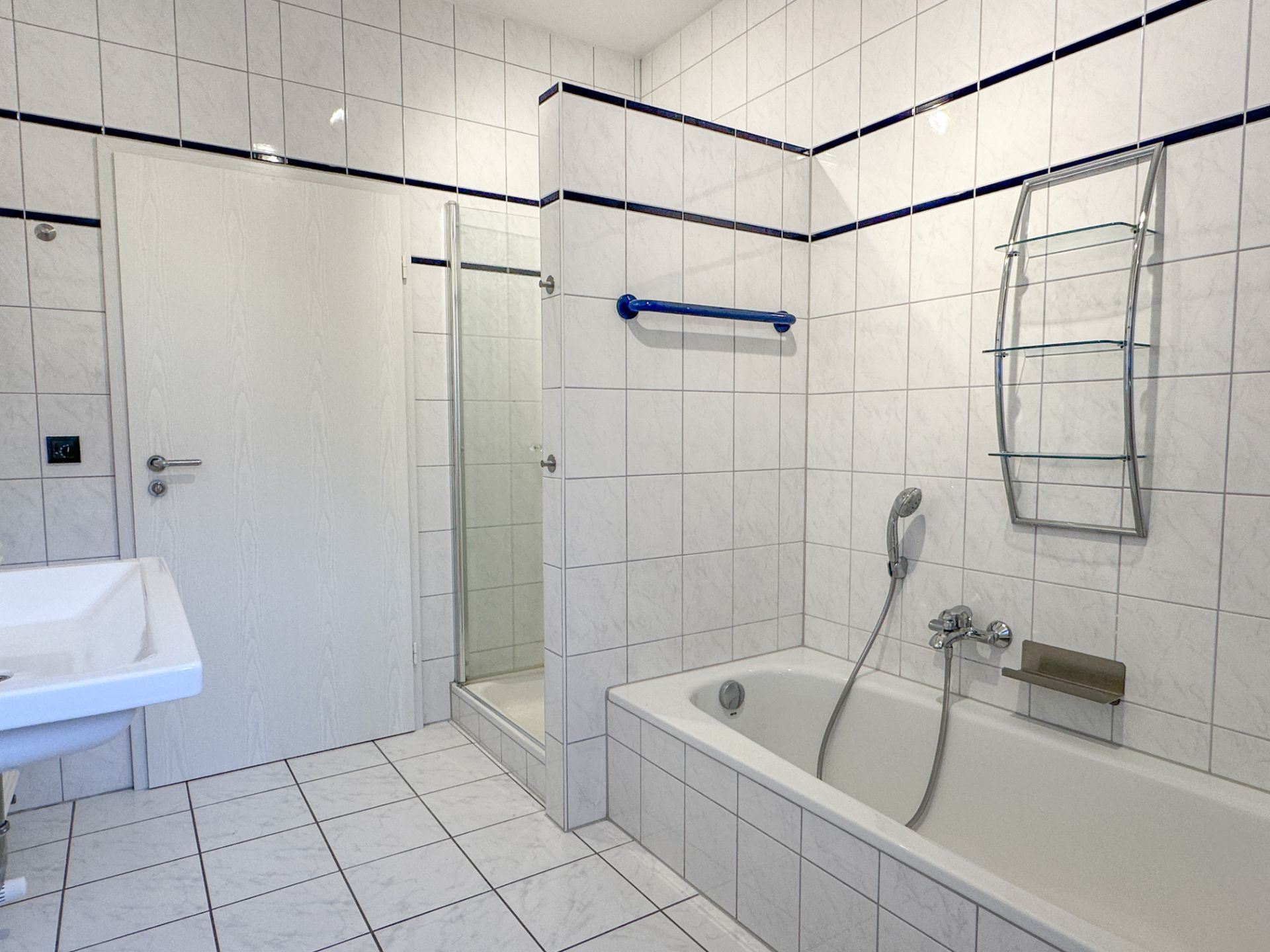 Modernes Badezimmer mit Badewanne, Dusche, Waschbecken und weißen Fliesen.