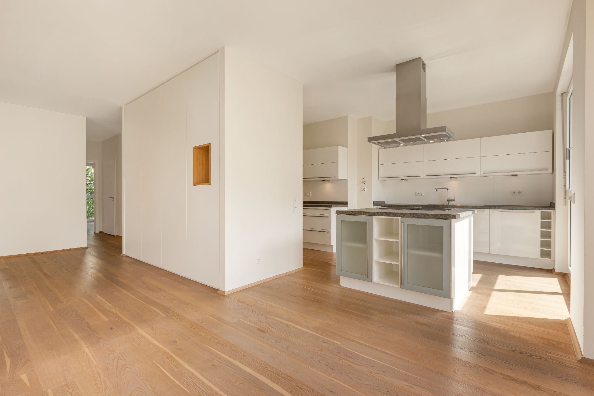 Helle, moderne Einbauküche mit Kücheninsel und offenem Wohnbereich auf Holzfußboden.