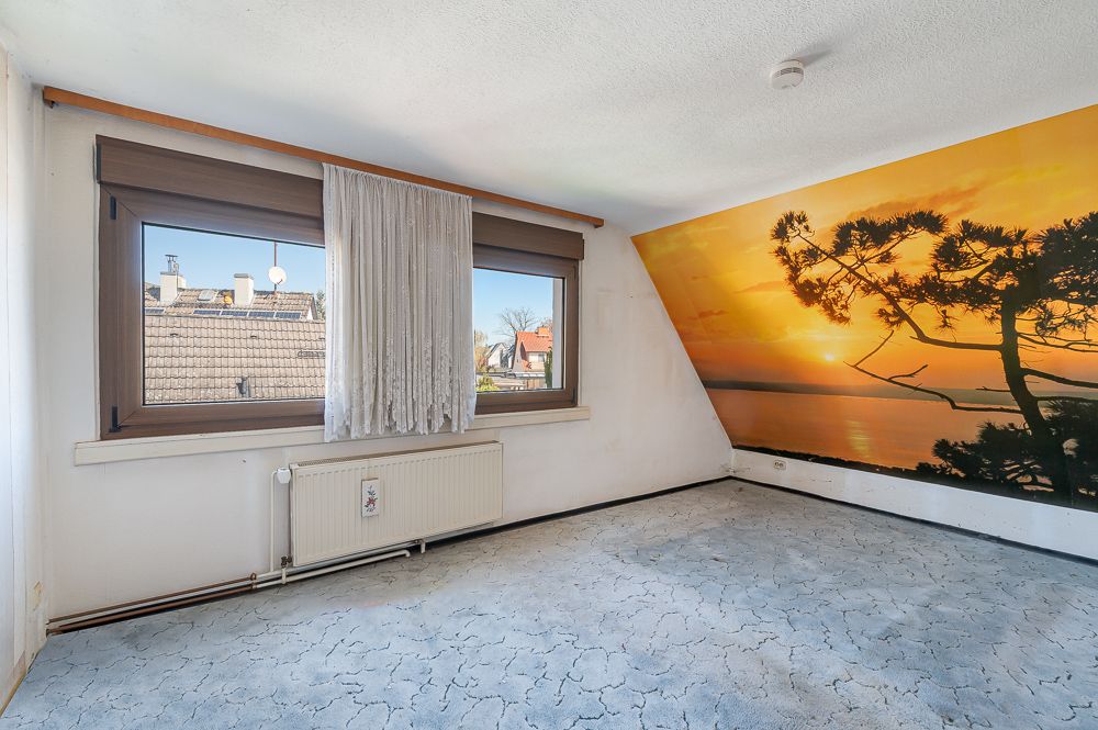 Helles Zimmer mit zwei Fenstern, Heizkörper und Wandbild mit Sonnenuntergang.