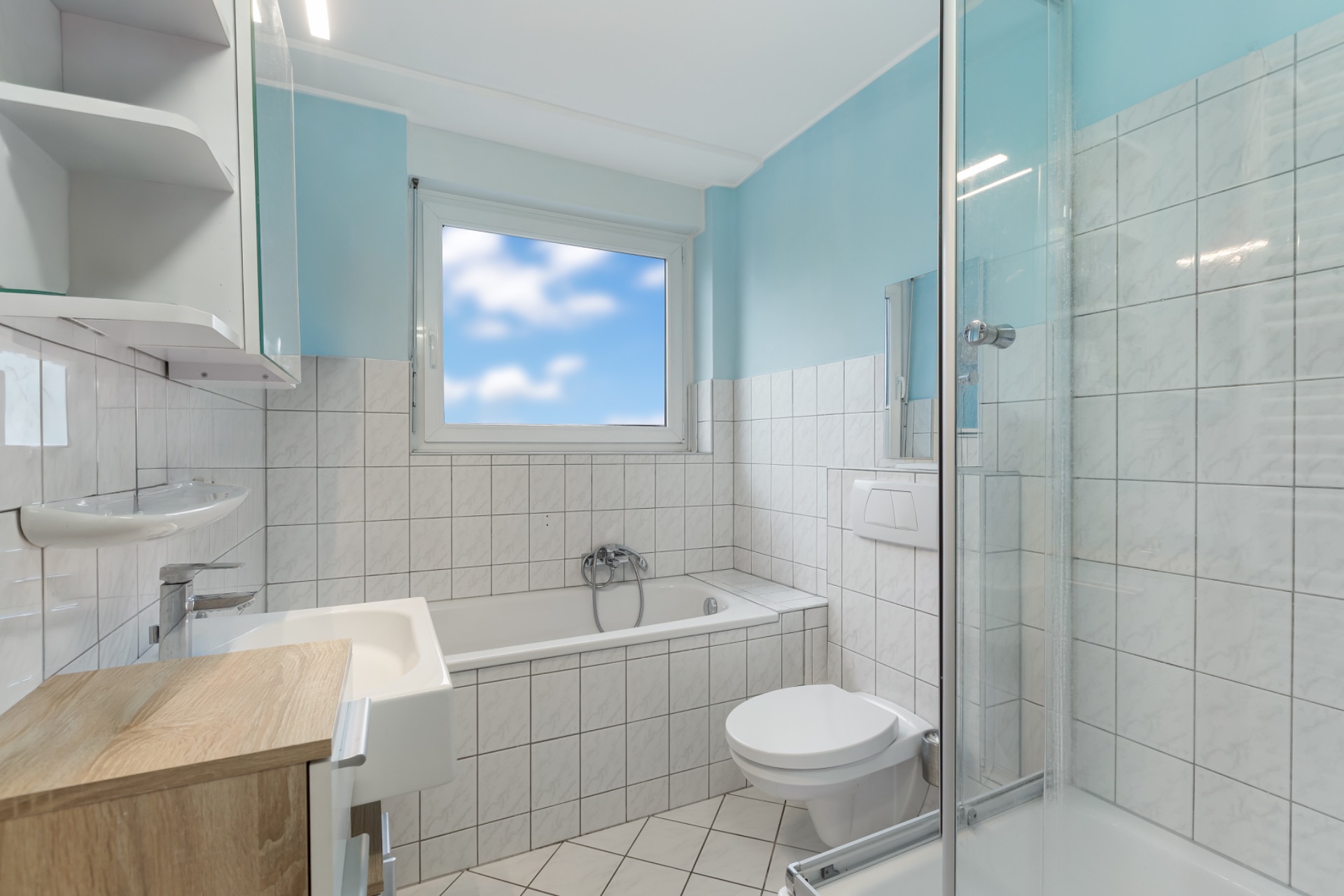 Modernes Badezimmer mit Badewanne, Dusche, WC, Waschbecken und Fenster.