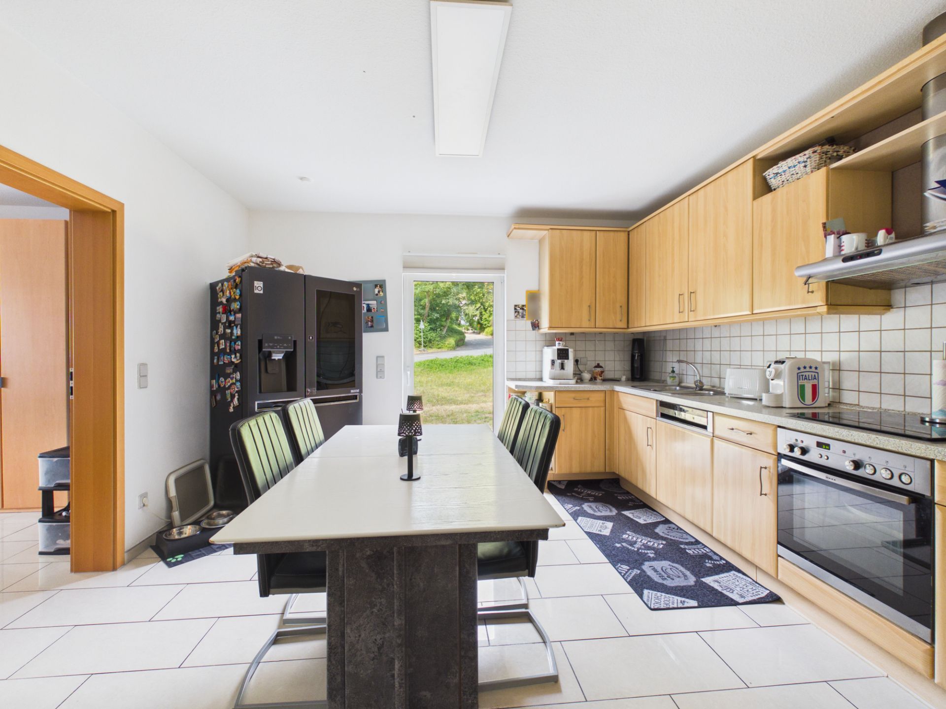 Moderne Küche mit Esstisch, vier Stühlen, Holzschränken und großem Kühlschrank.