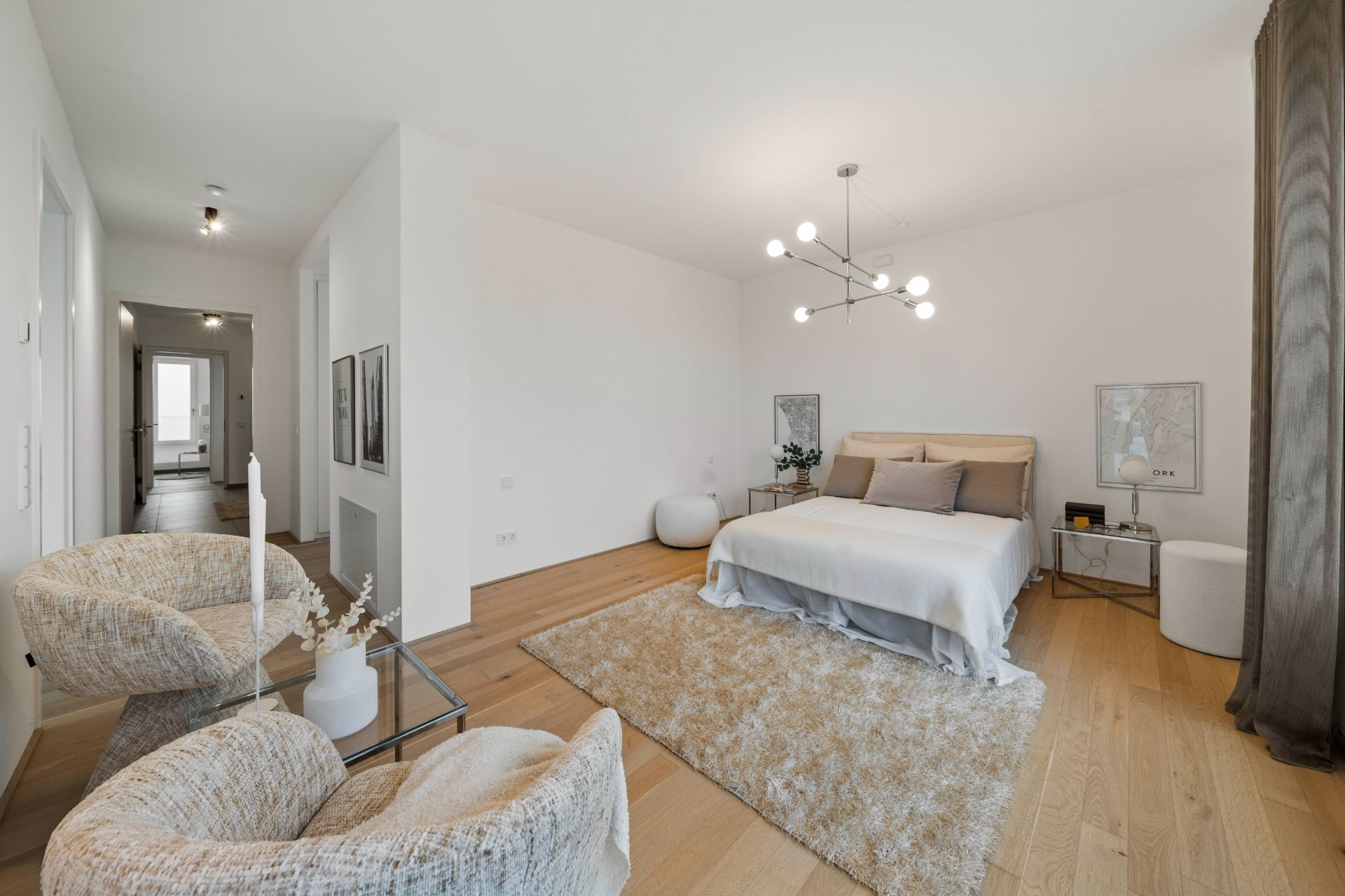 Modernes Schlafzimmer mit Doppelbett, zwei Sesseln, Teppich und großer Fensterfront.
