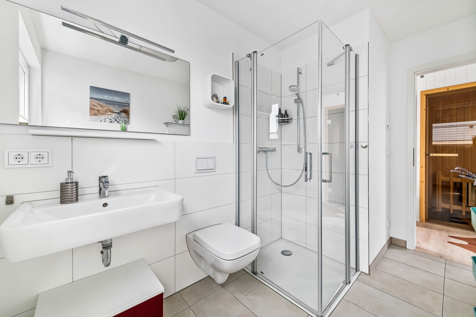 Modernes Badezimmer mit Dusche, Waschbecken, WC und großem Spiegel.