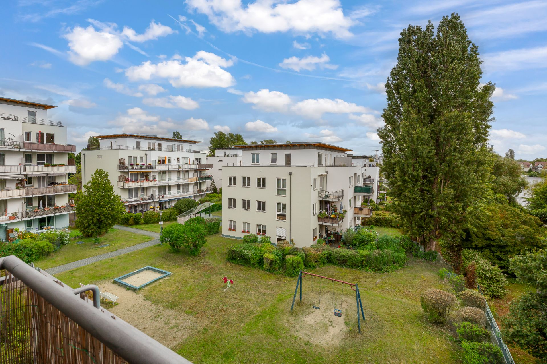 Mehrere Wohngebäude mit Balkonen und einem kleinen Spielplatz im begrünten Innenhof.